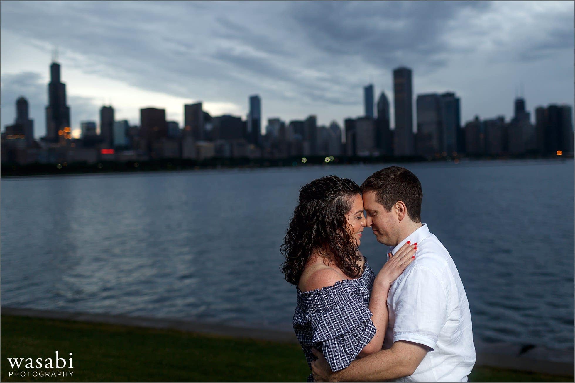 a couple laughs during their engagement session at Adler Planetarium overlooking Chicagos skyline
