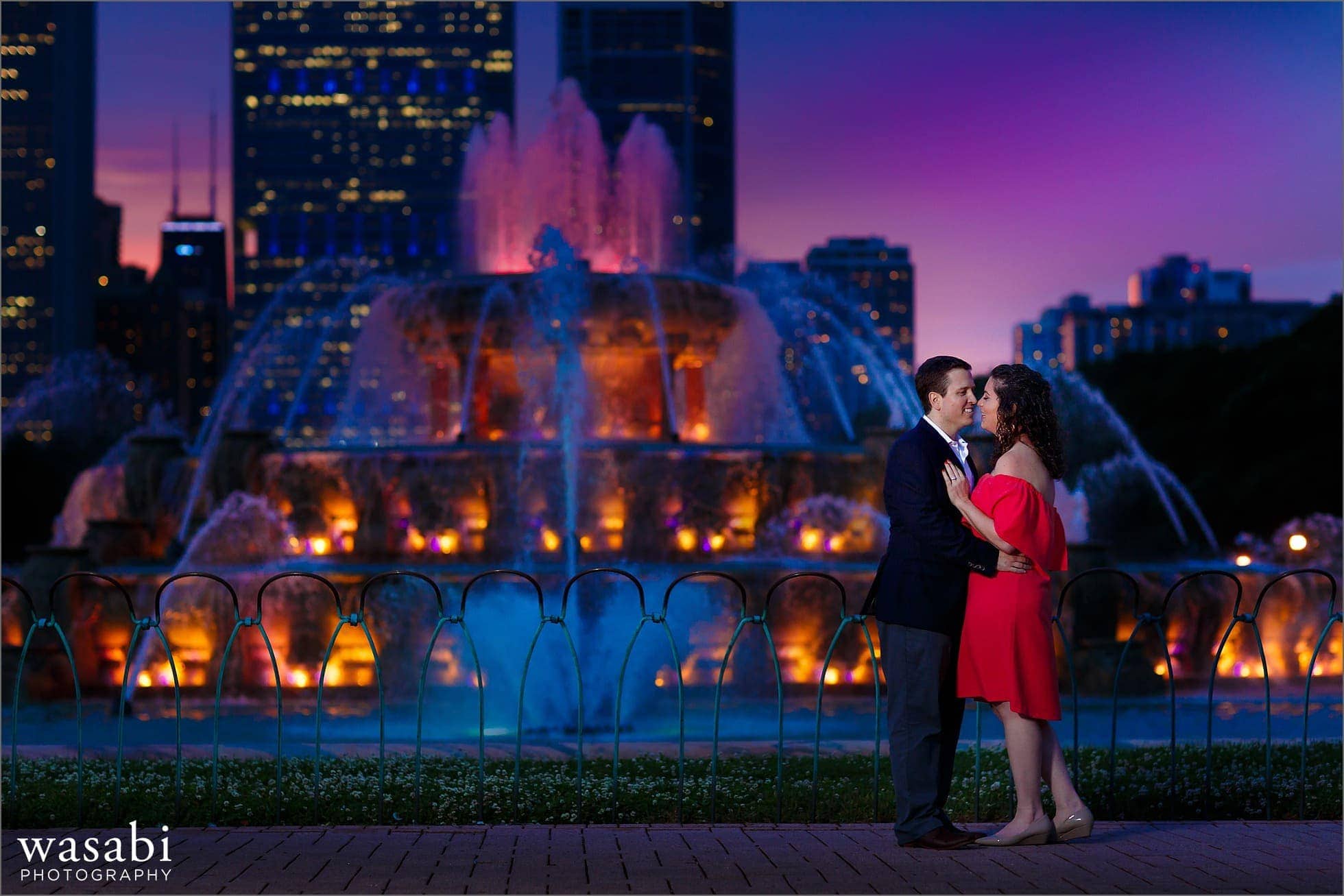 a couple laughs together during their Buckingham Fountain engagement photos night engagement session in downtown Chicago