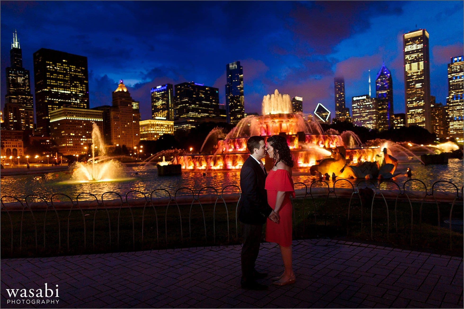 a couple takes night engagement photos at Buckingham Fountain in downtown Chicago