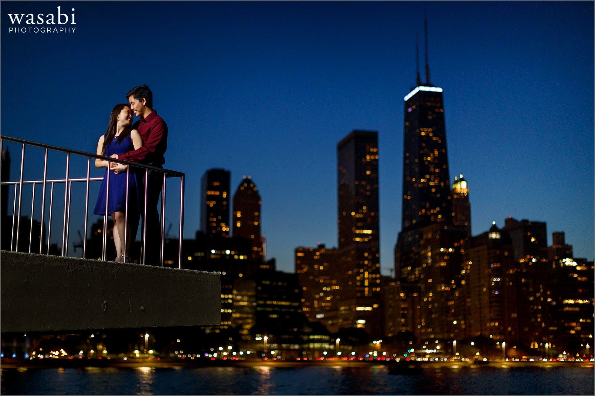 couple poses during Olive Park engagement photos with Chicago skyline in background