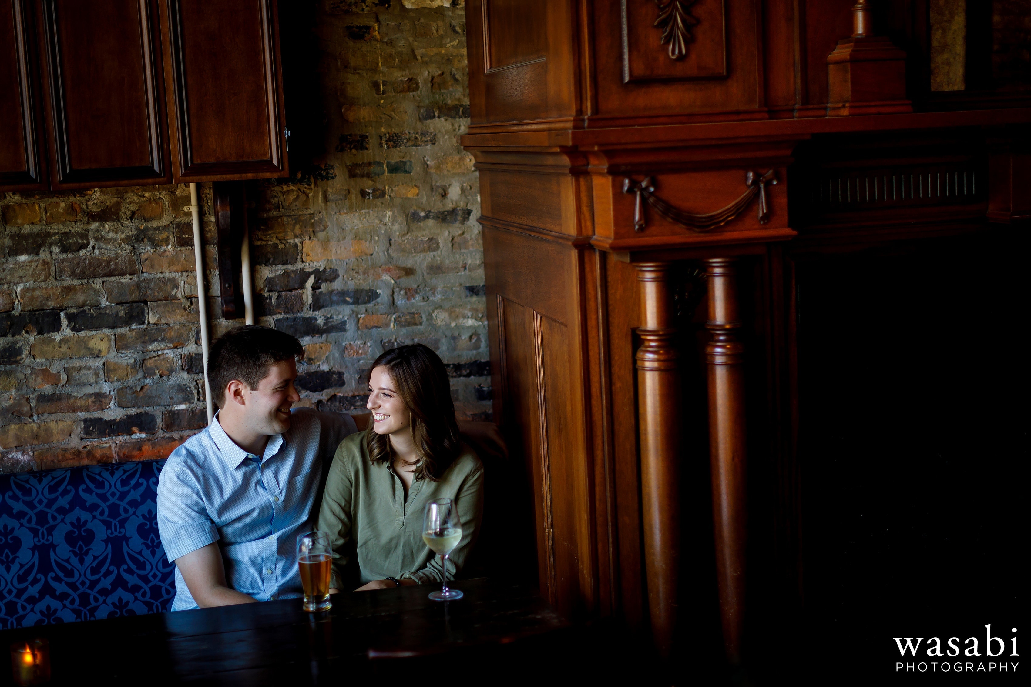 A couple laughs over drinks at Old Town Social during their engagement session in Chicagos Old Town neighborhood