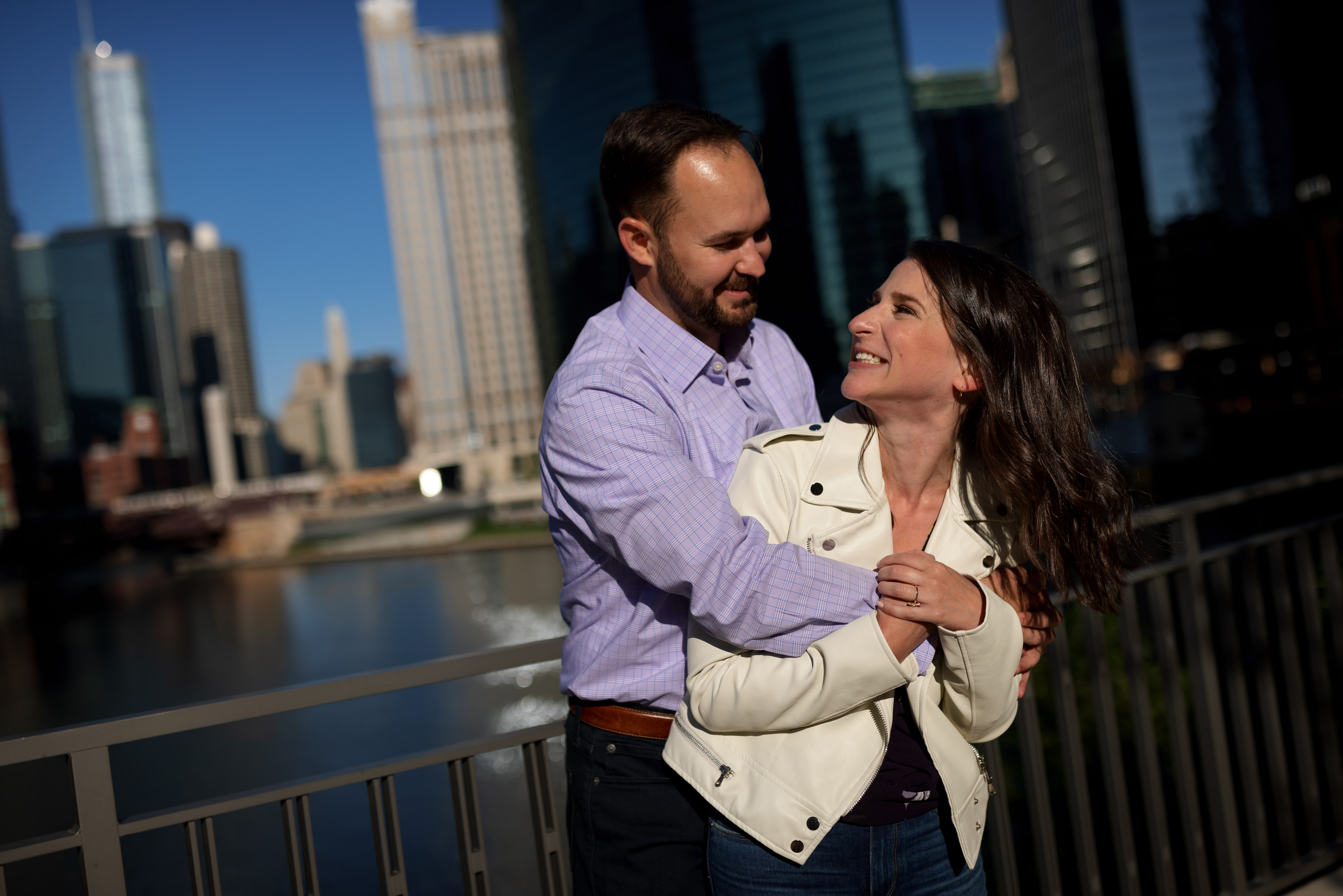 couple poses for engagement photos with Chicago river in background at Wolf Point near Gibson's Italia