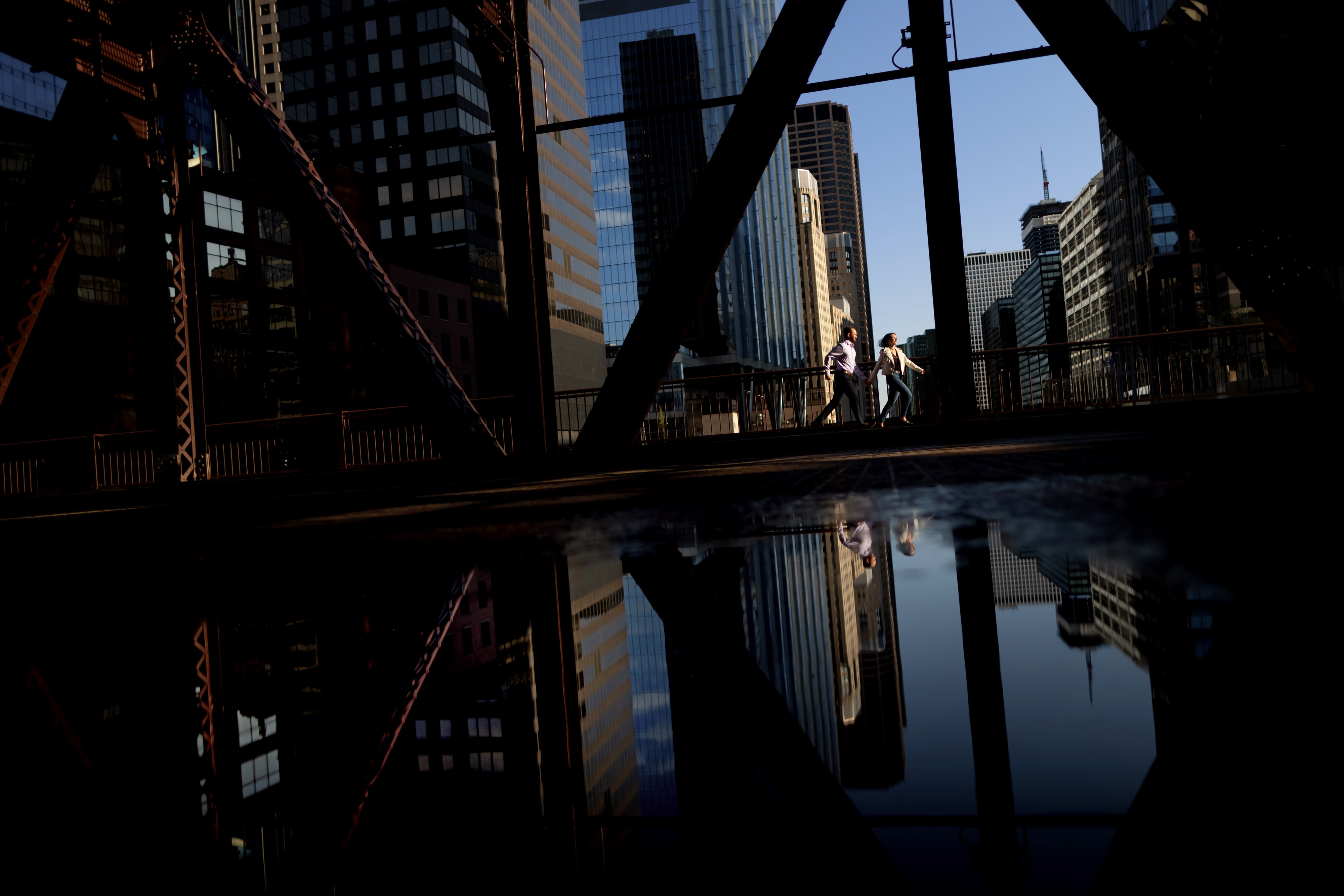 couple runs along Lake Street over the Chicago river near Wolf Point during engagement photos in downtown Chicago