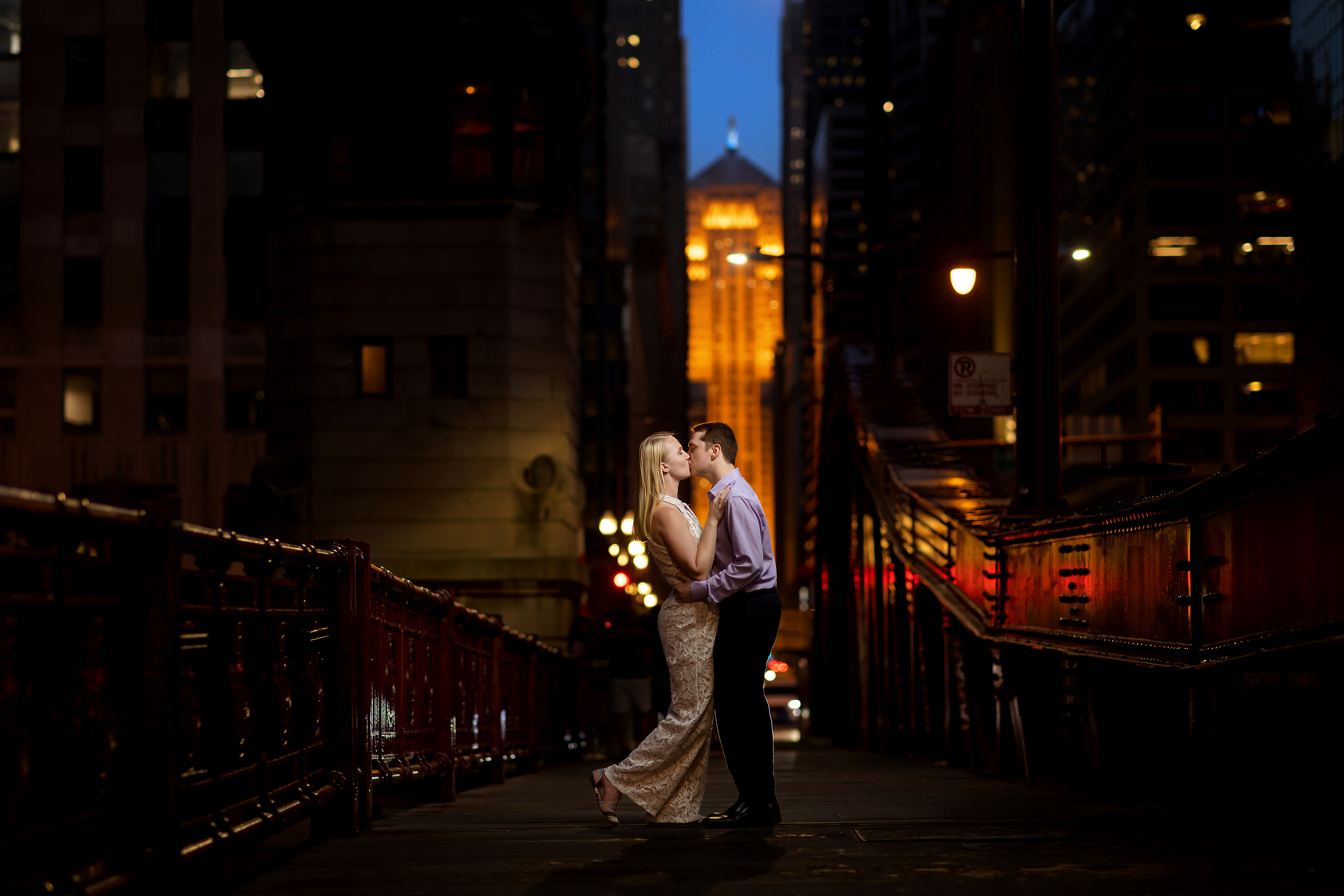 couple kisses on LaSalle Street Bridge during summer engagement session at night in downtown Chicago
