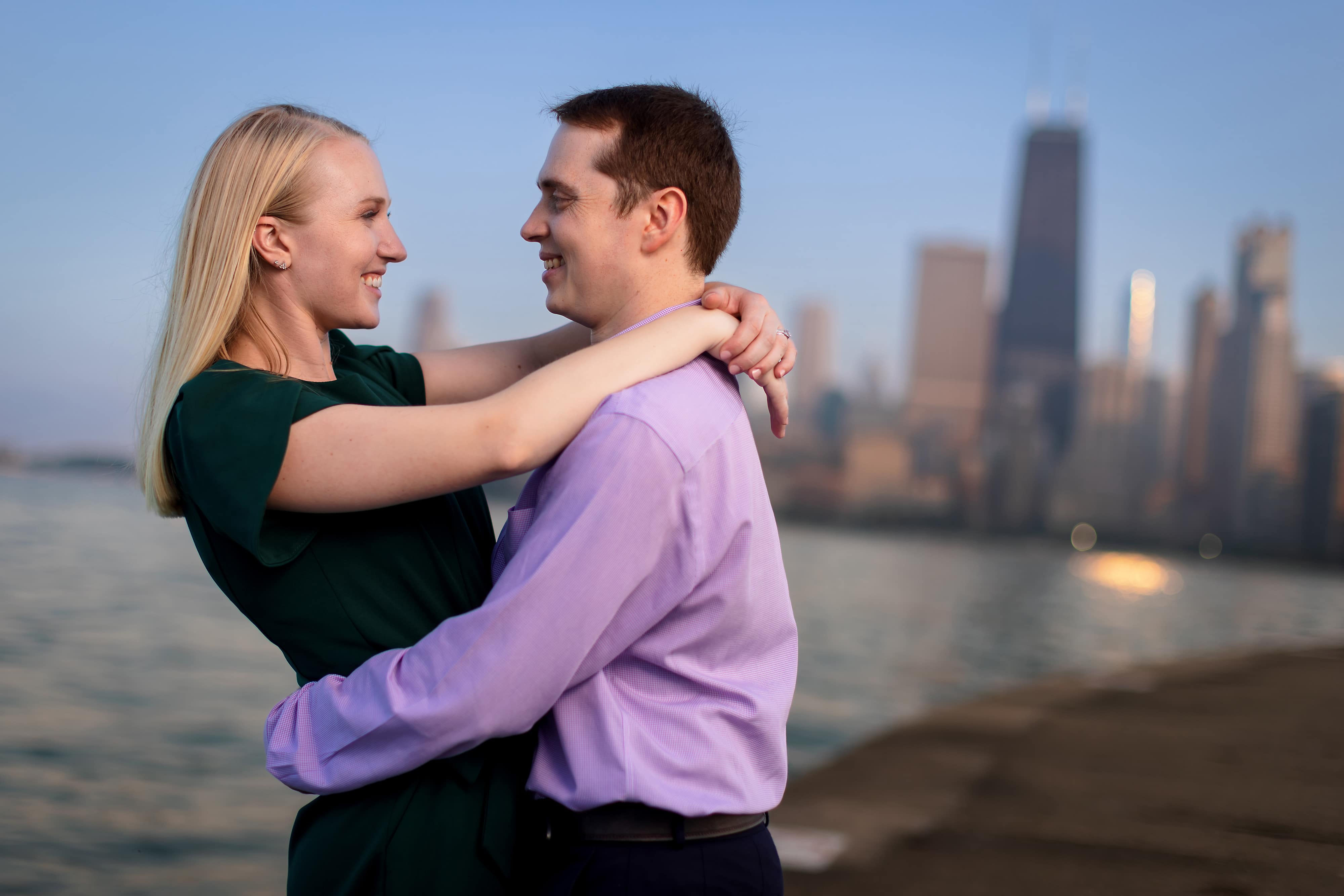 couple hugs during engagement session along Lake Michigan at North Avenue Beach in Chicago during a summertime engagement session