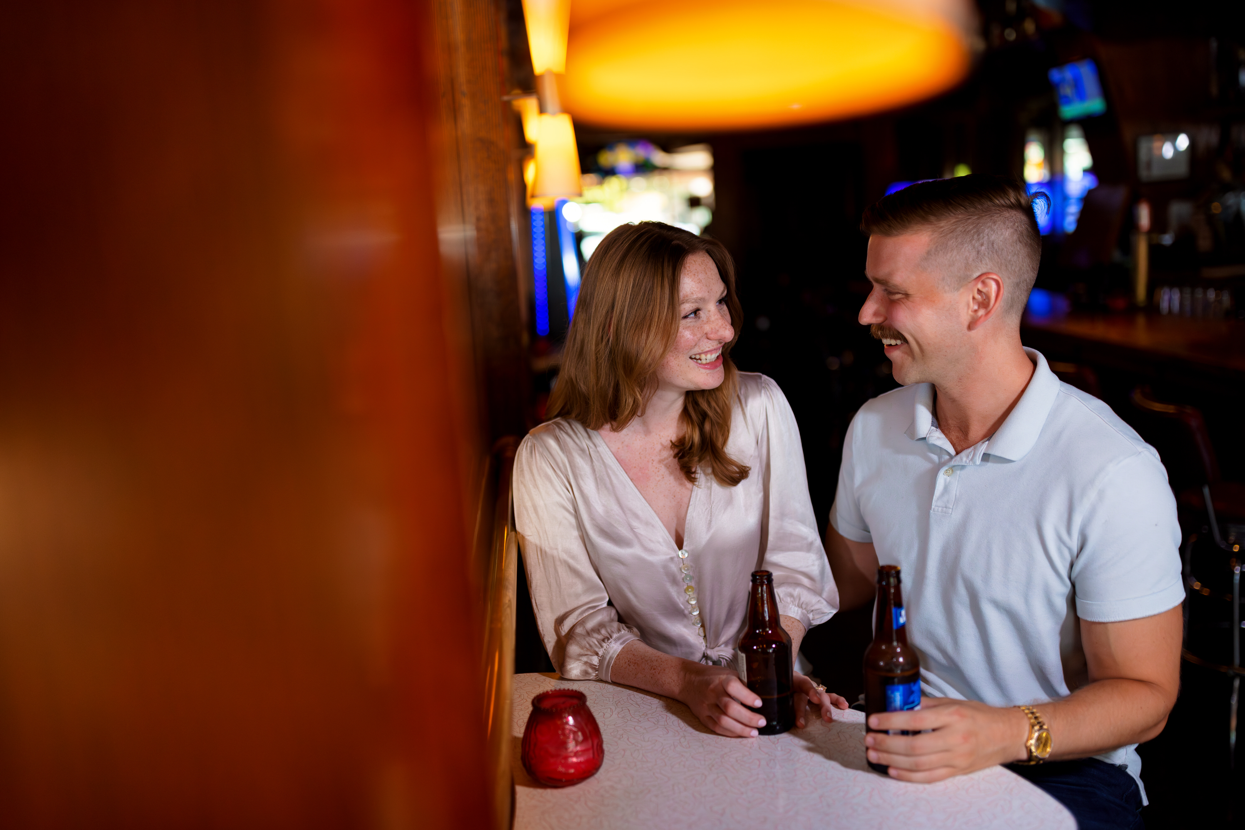 Couple shares beers at a bar during an engagement session in Chicago's Lincoln Park neighborhood