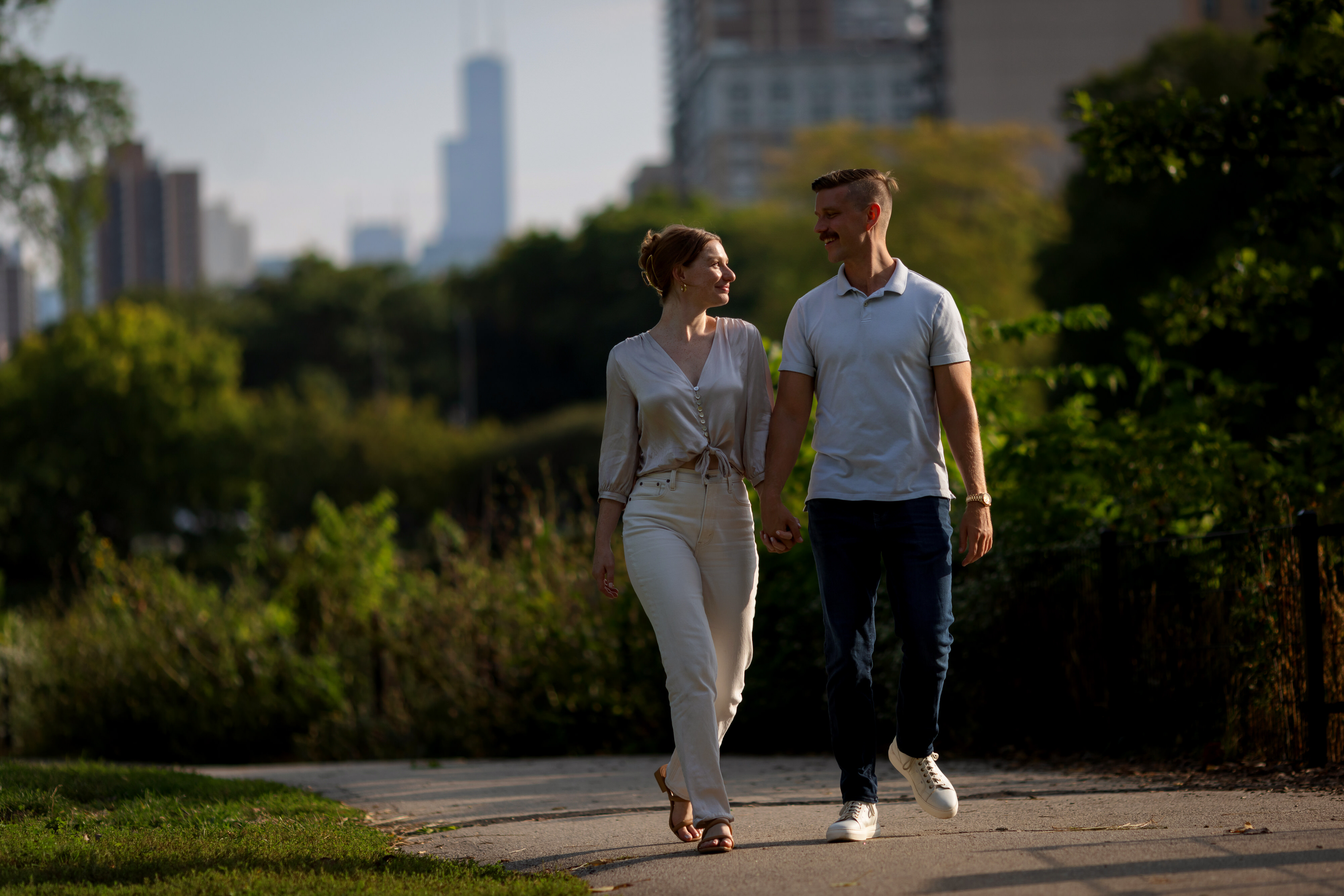 Couple holds hands while walking through Lincoln Park during engagement session