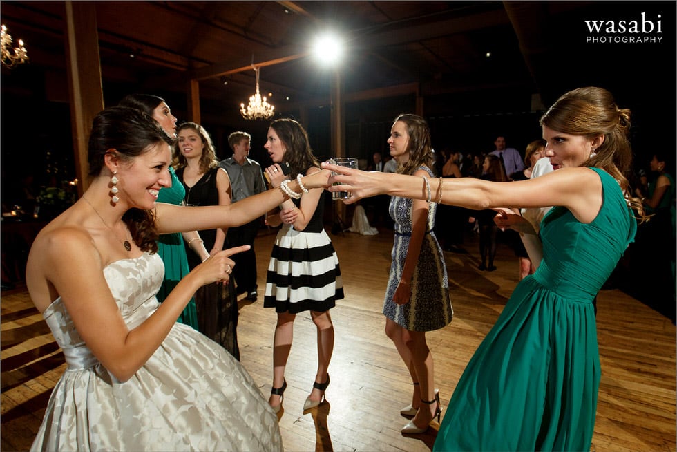 bride and bridesmaids pointing at each other while dancing during wedding reception