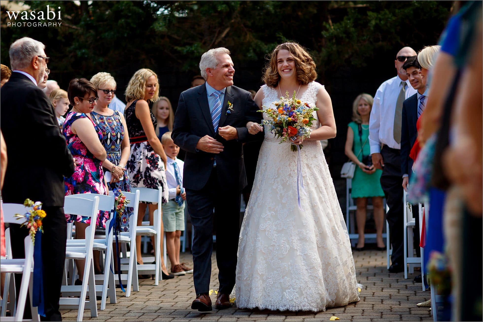bride and father walk down the aisle during wedding at Oakhurst Country Club in Clarkston, Michigan