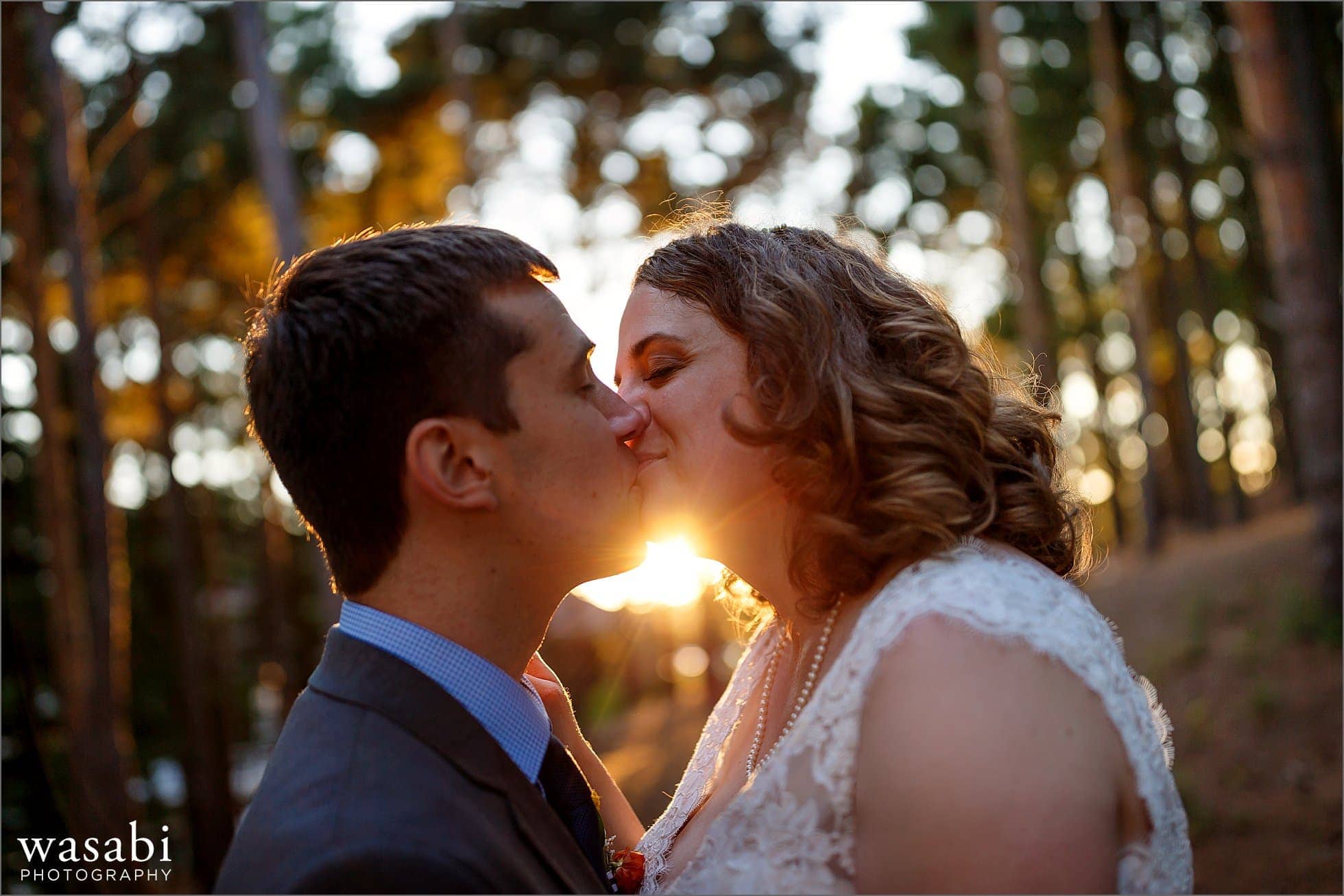 bride and groom kiss during Oakhurst Country Club wedding photos portrait session in pine trees 