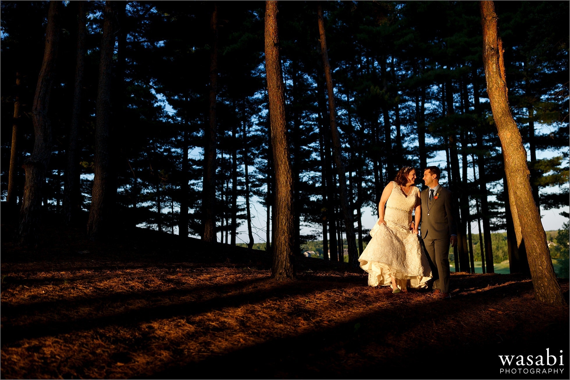 bride and groom walk through pine tree forest in sweet light magic hour at Oakhurst Country Club wedding photos