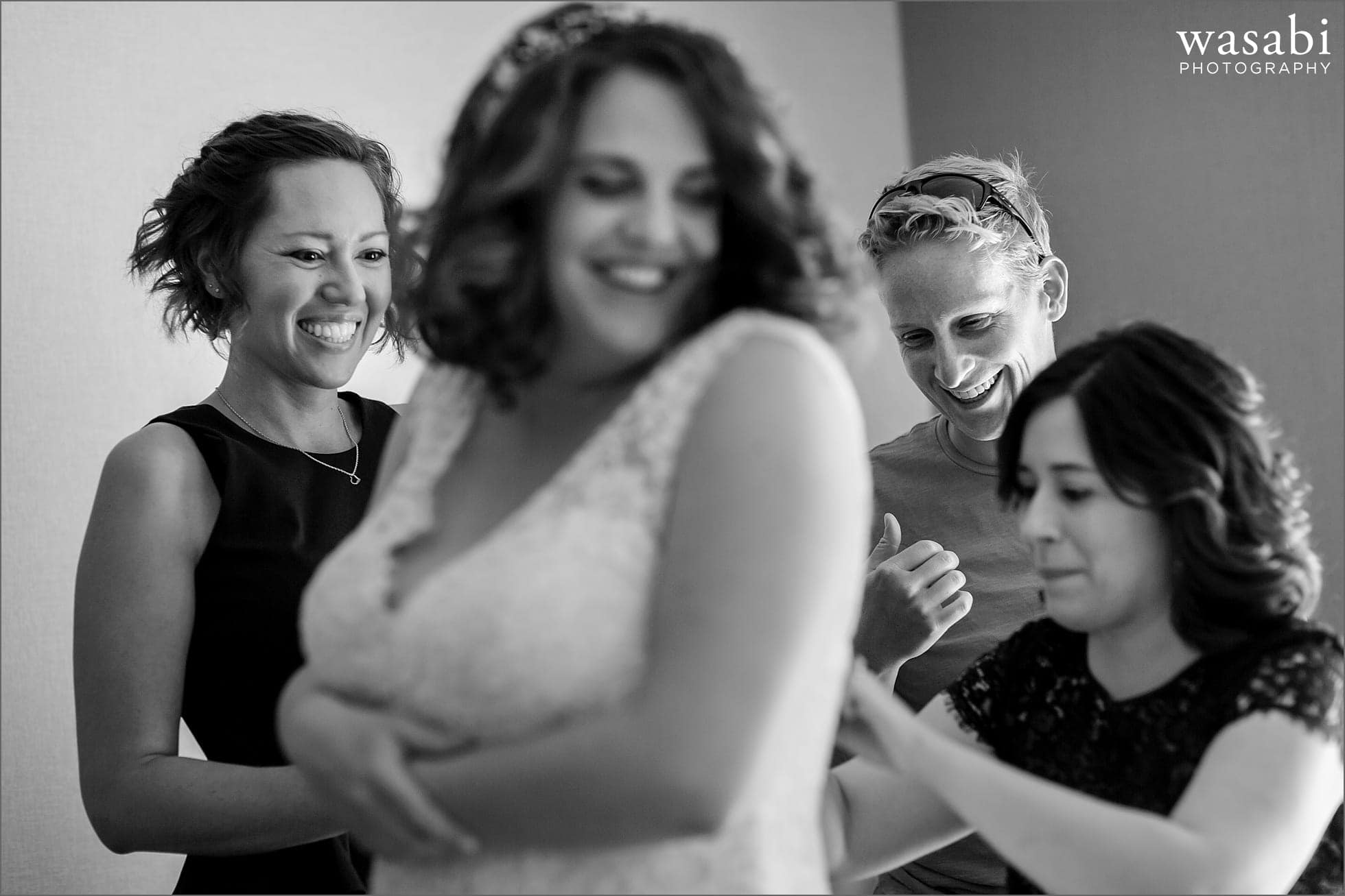 bridesmaids help bride into dress before her wedding at Oakhurst Country Club in Clarkston, Michigan