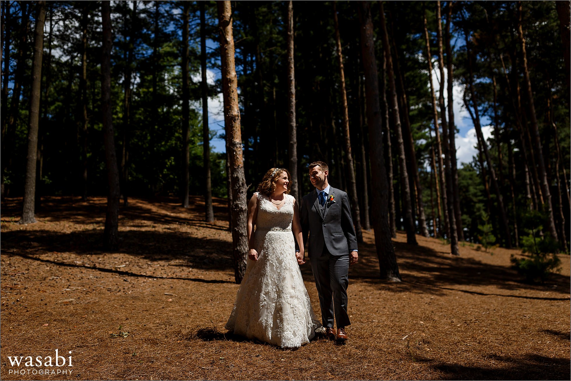 wedding couple walks through a forest of oak trees at Oakhurst Country Club in Clarkston, Michigan