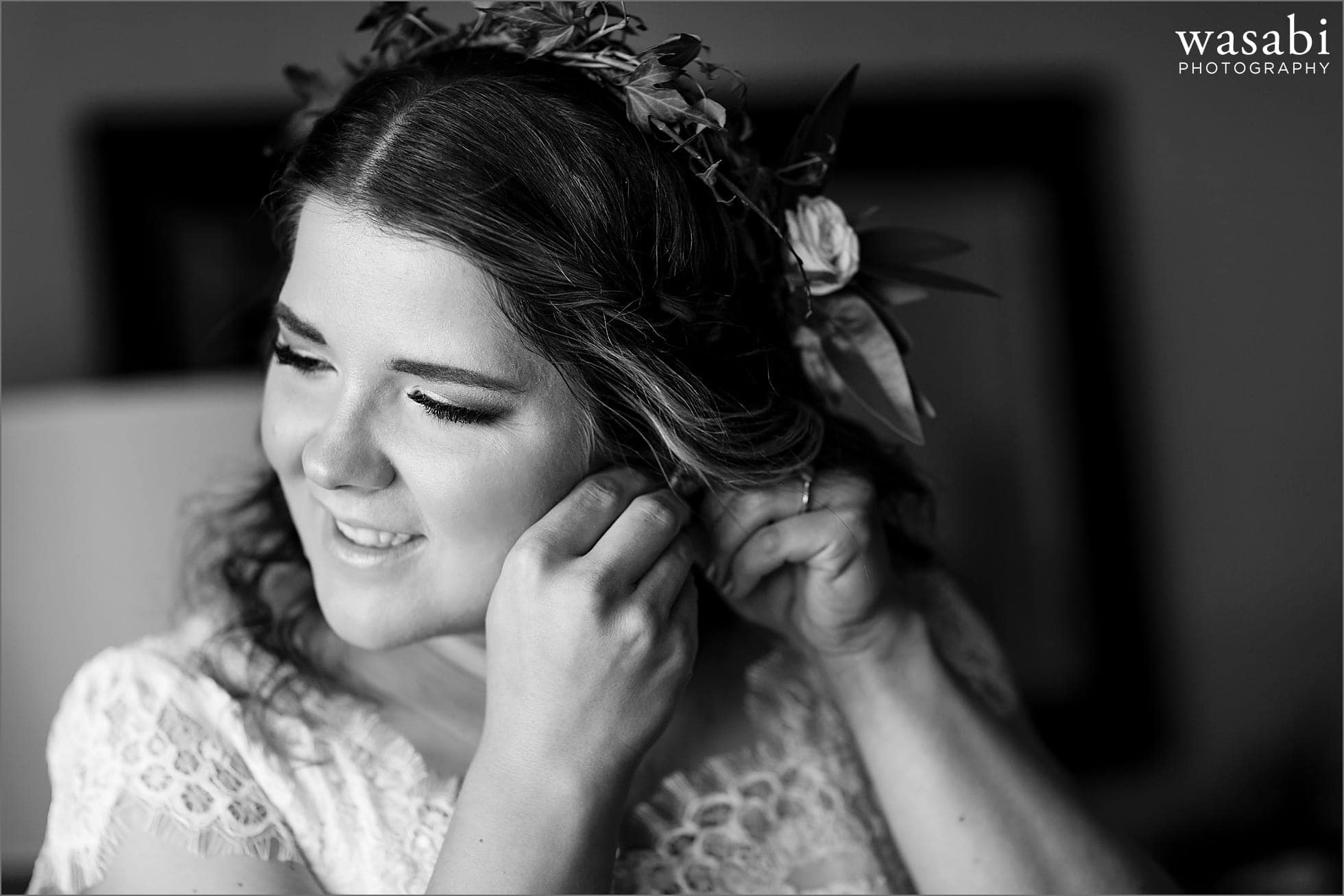 bride puts on earrings while getting ready for her wedding at DoubleTree Inn in Alsip