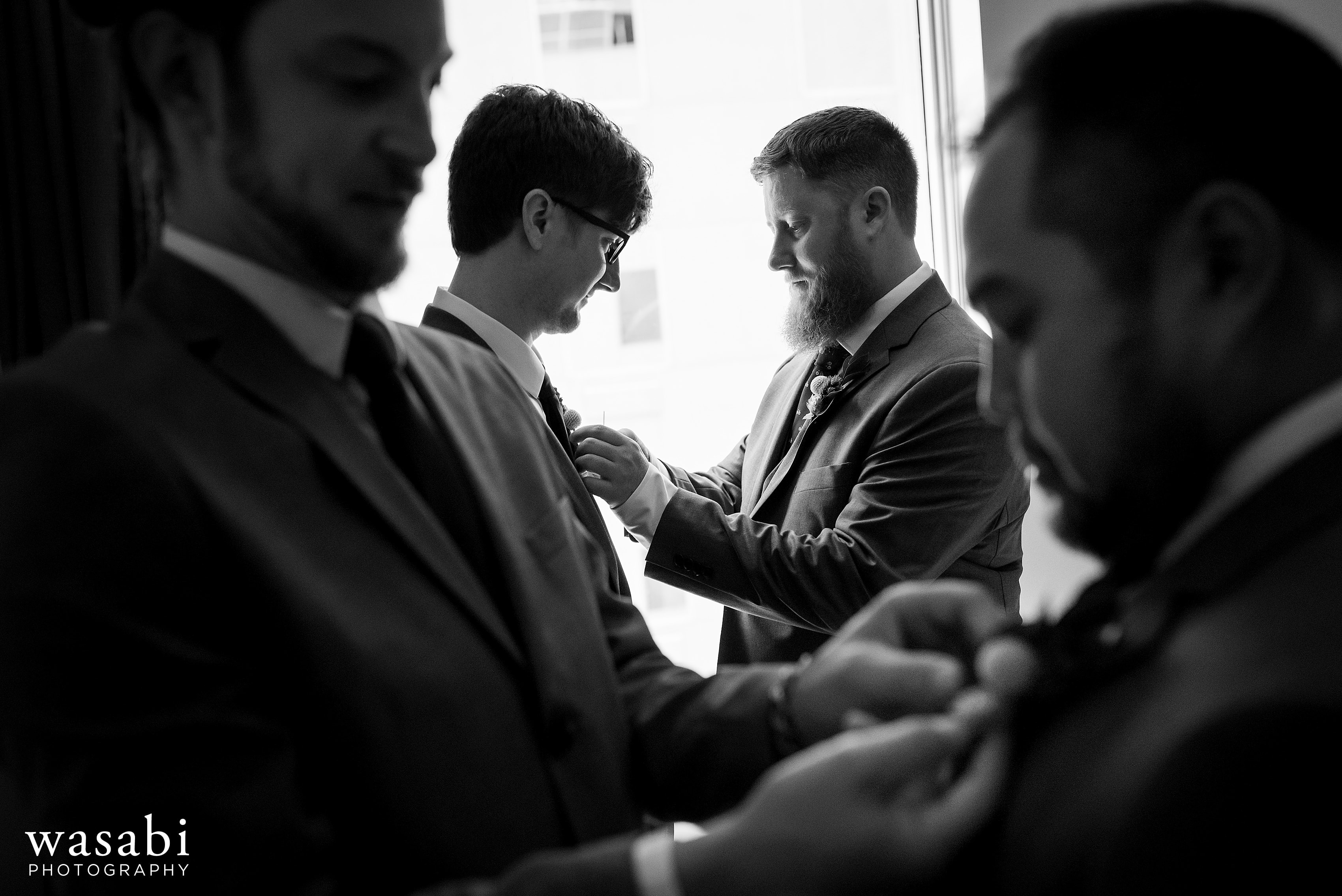 Groomsmen put their boutonnières on while getting ready for a wedding at La Quinta Inn & Suites in downtown Chicago