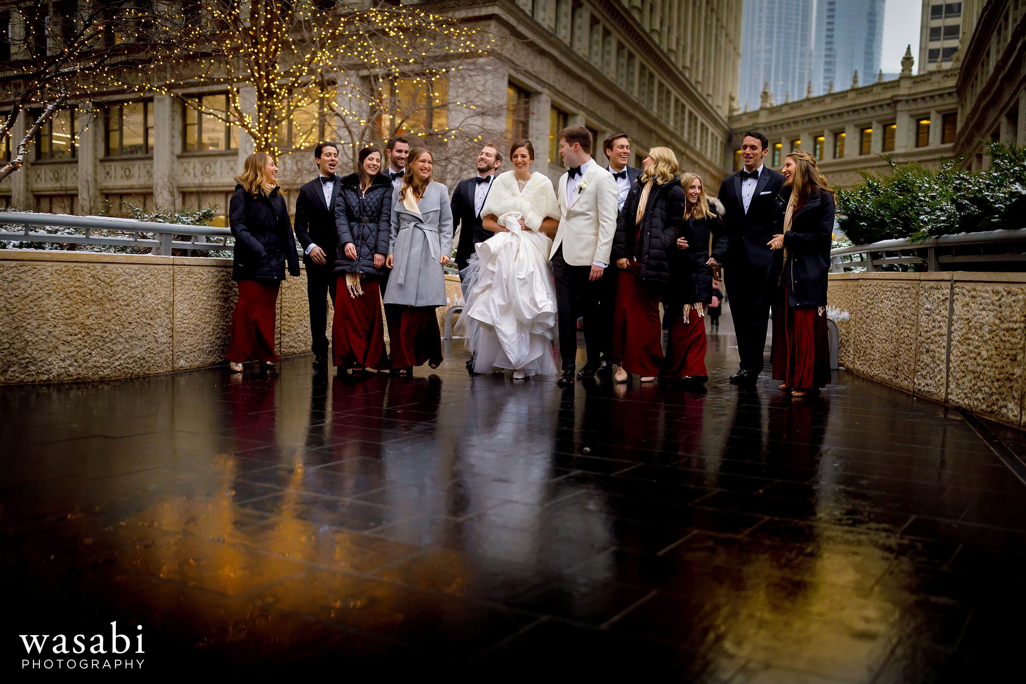 wedding party walks under the Wrigley Building in downtown Chicago during winter wedding