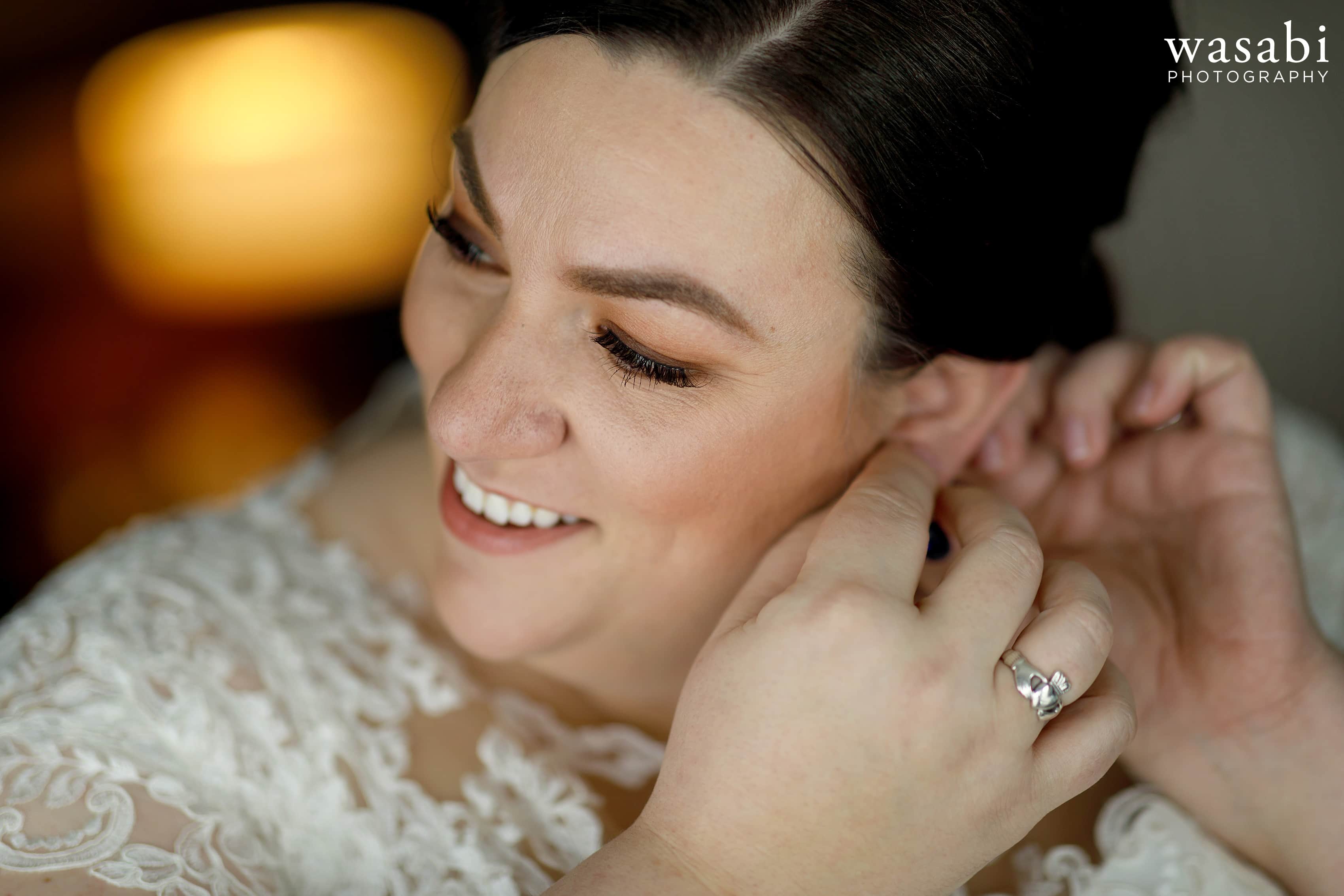 bride puts earring on while getting ready for wedding