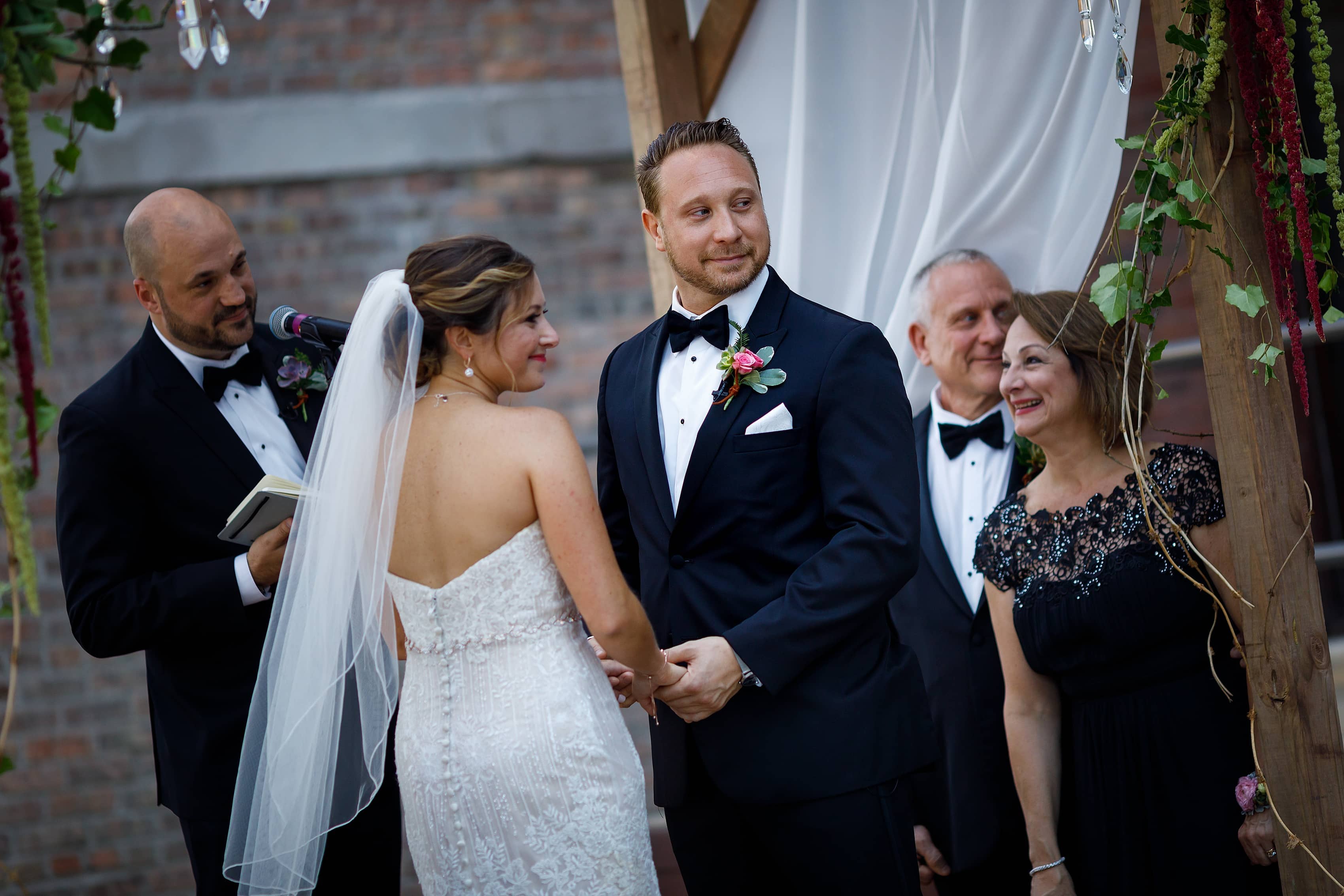 bride and groom smile during wedding ceremony at Bridgeport Art Center Sculpture Garden in Chicago