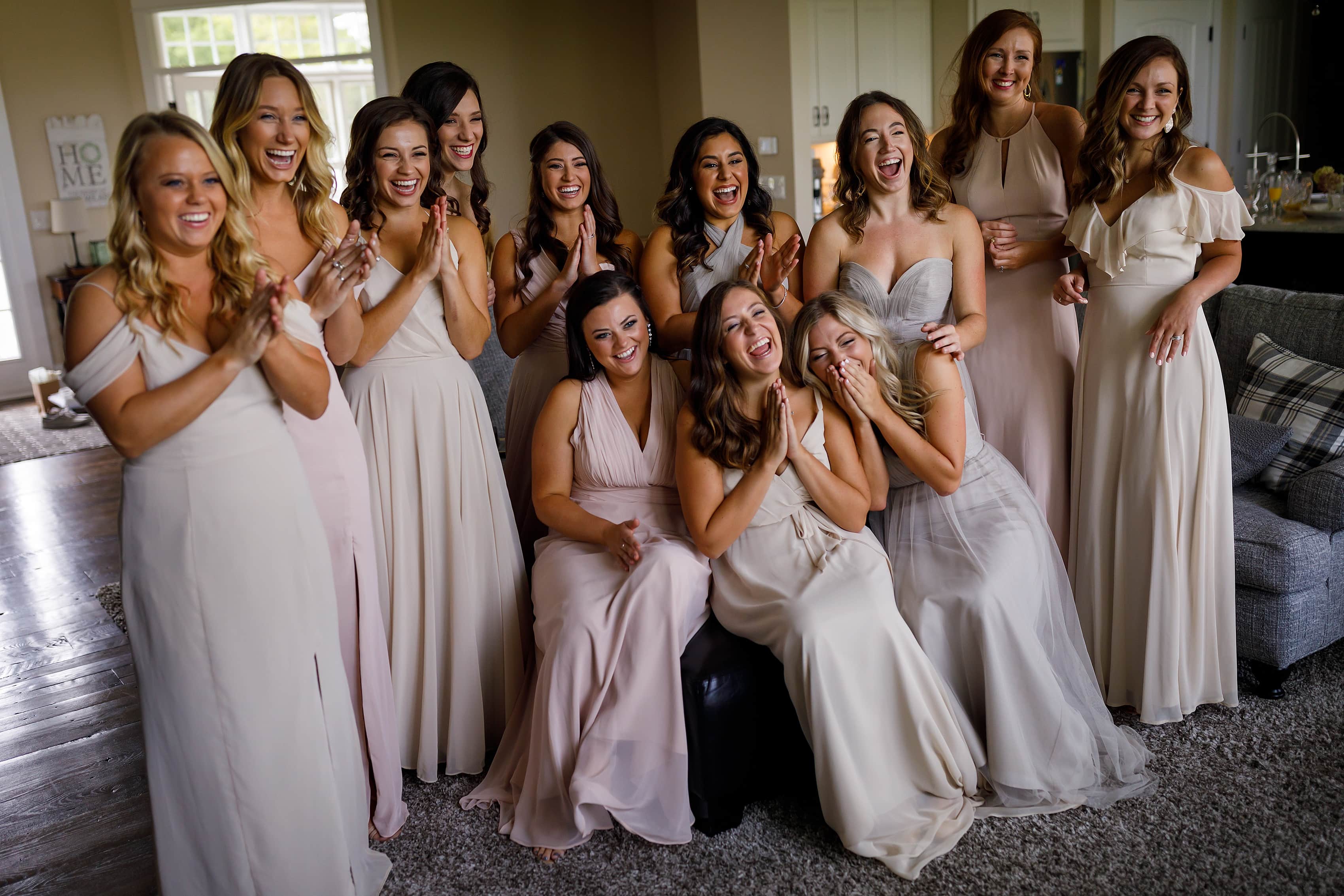 Group of bridesmaids reacts to seeing bride in her dress while getting ready for wedding