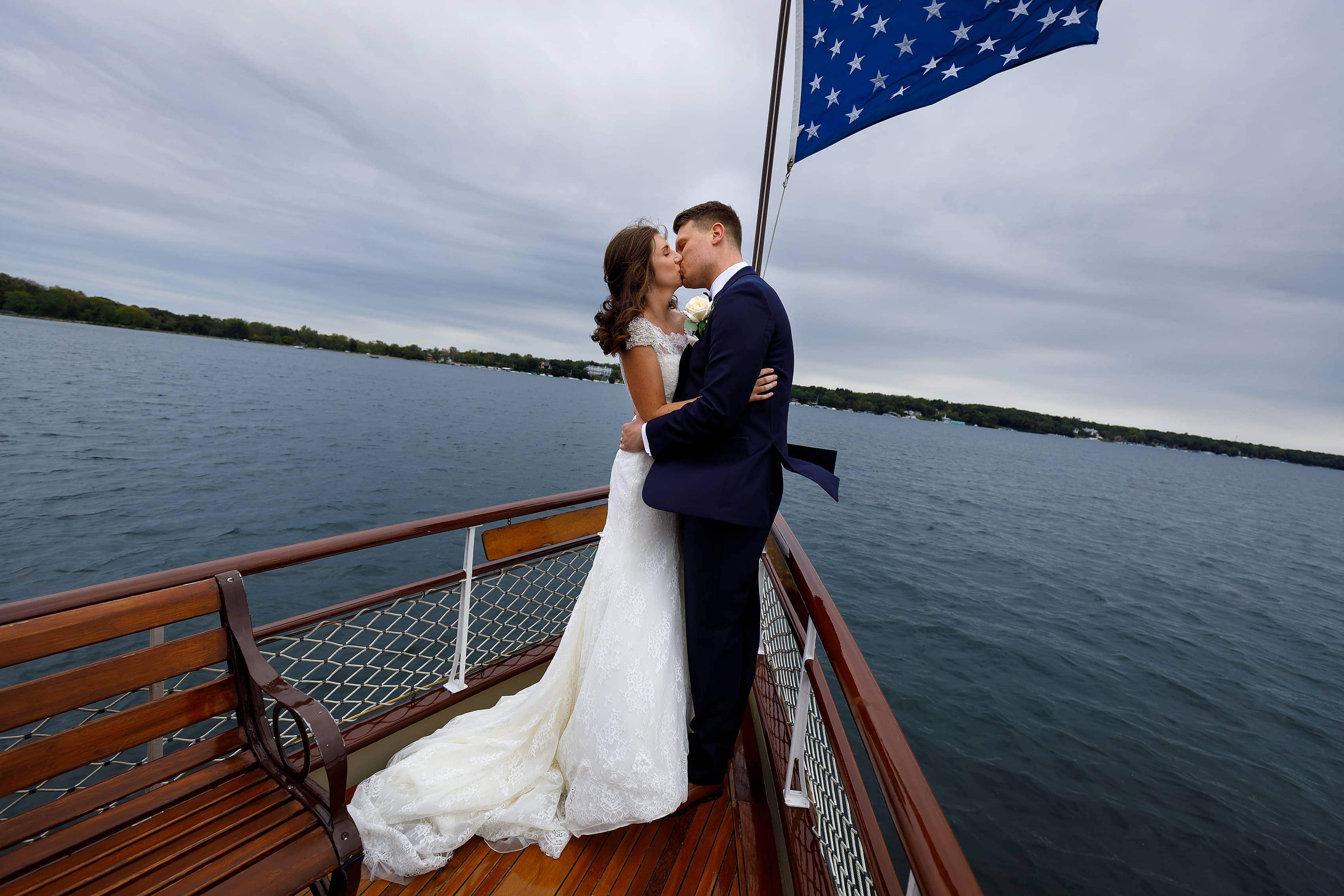 Bride and groom pose for a photo on a boat at Lake Geneva Yacht Club in Lake Geneva, Wisconsin