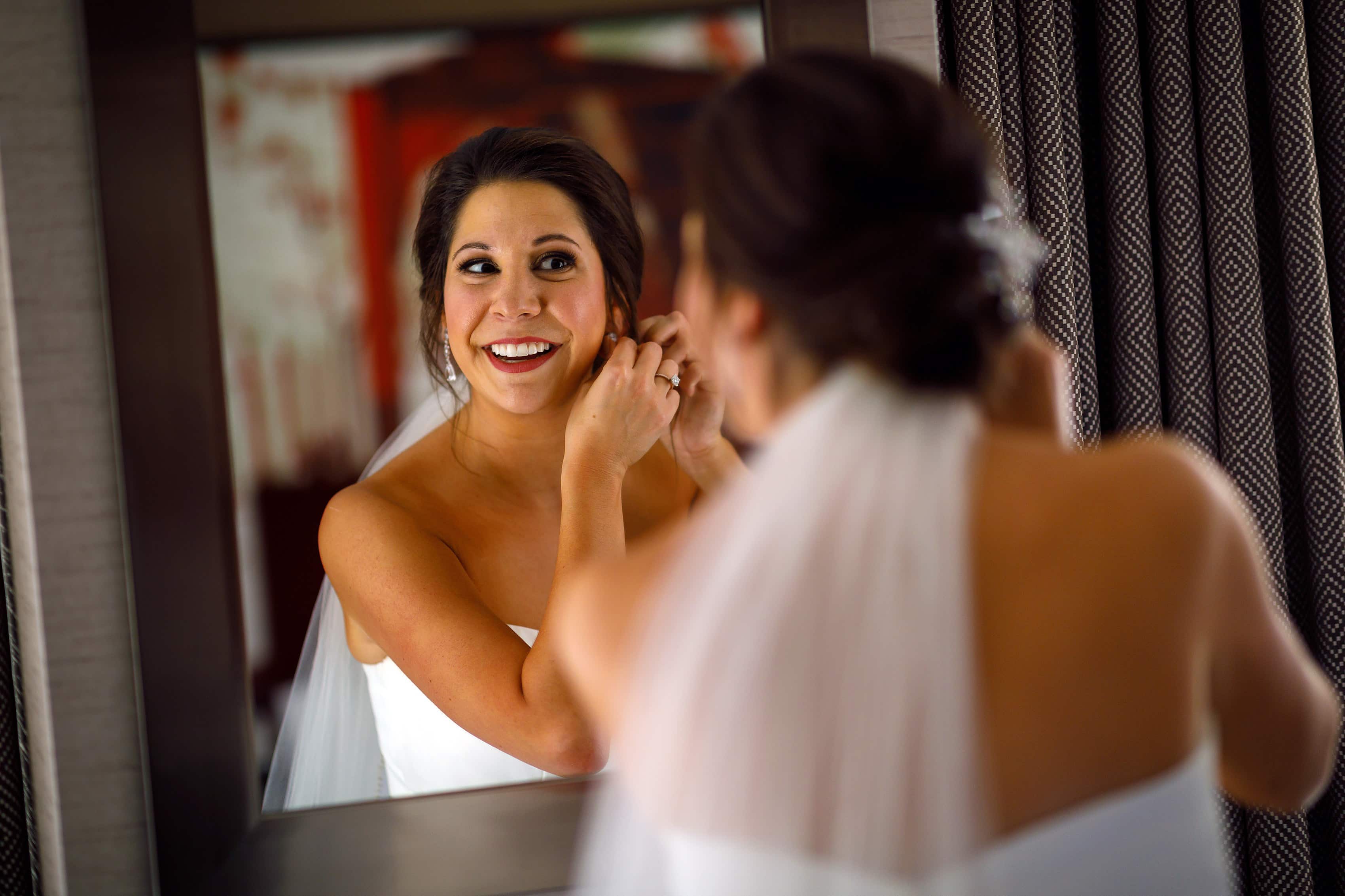 bride puts on earring while looking in mirror while getting ready at The Westin Michigan Ave for wedding at Holy Name Cathedral