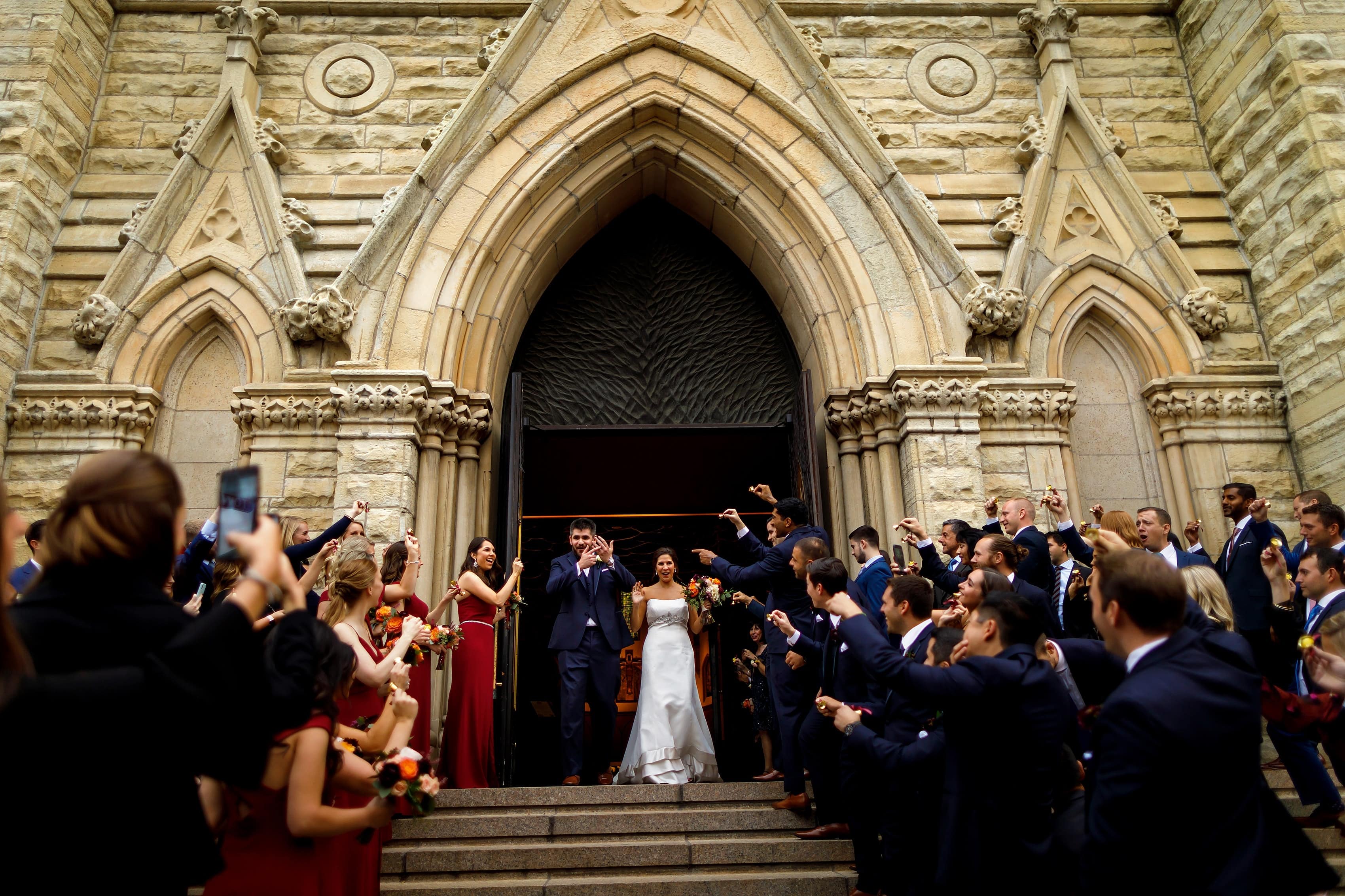 bride and groom walk outside to cheering guests after their wedding ceremony at Holy Name Cathedral in downtown Chicago