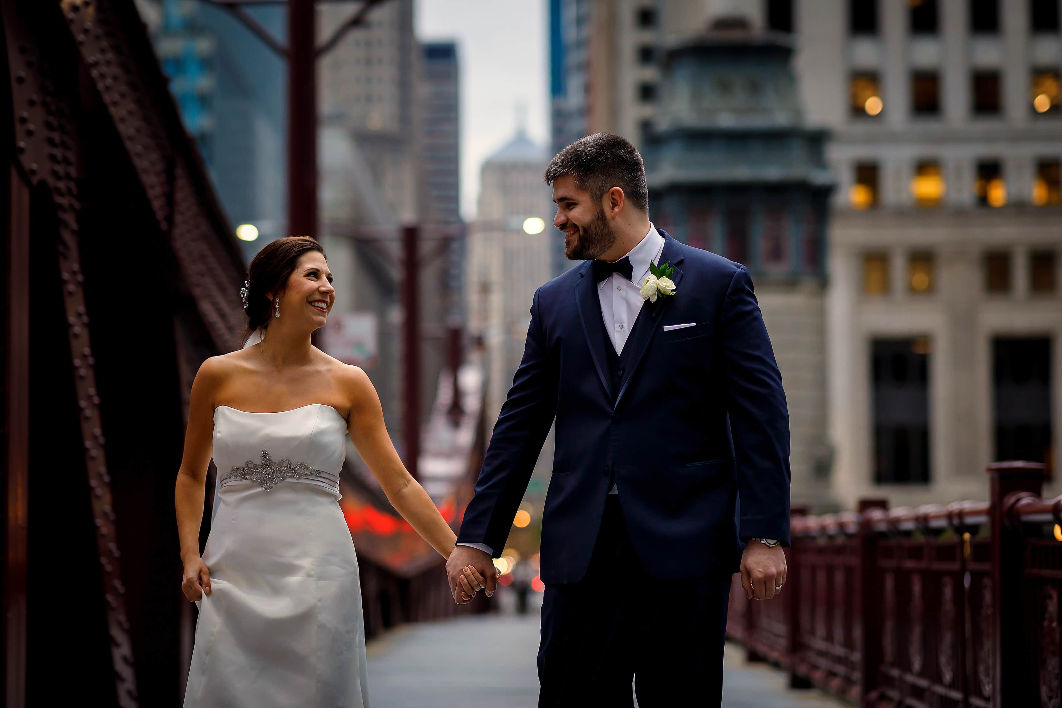 bride and groom walk down sidewalk on LaSalle Street bridge in downtown Chicago