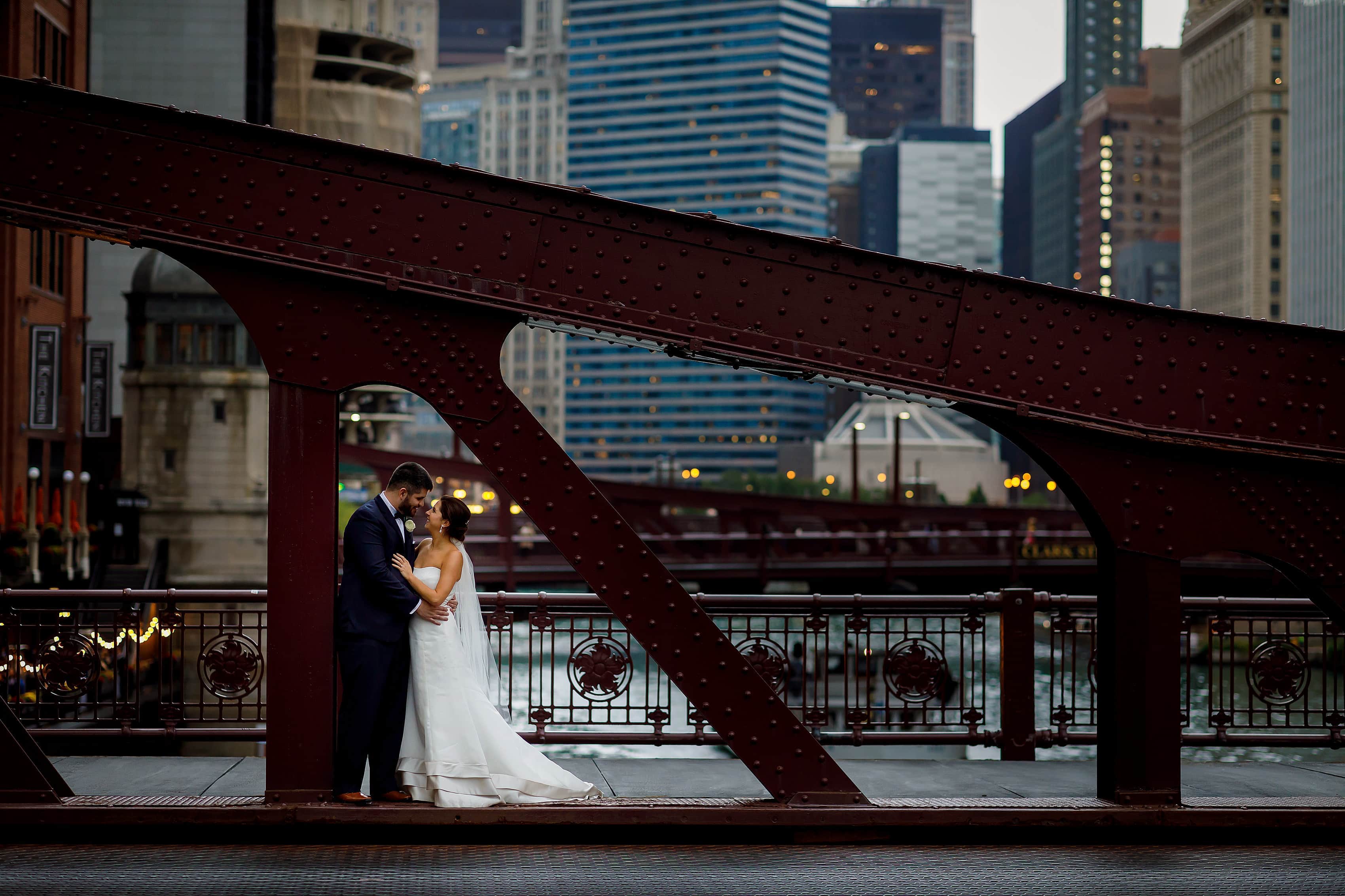 bride and groom pose for wedding photos on LaSalle Street bridge in downtown Chicago