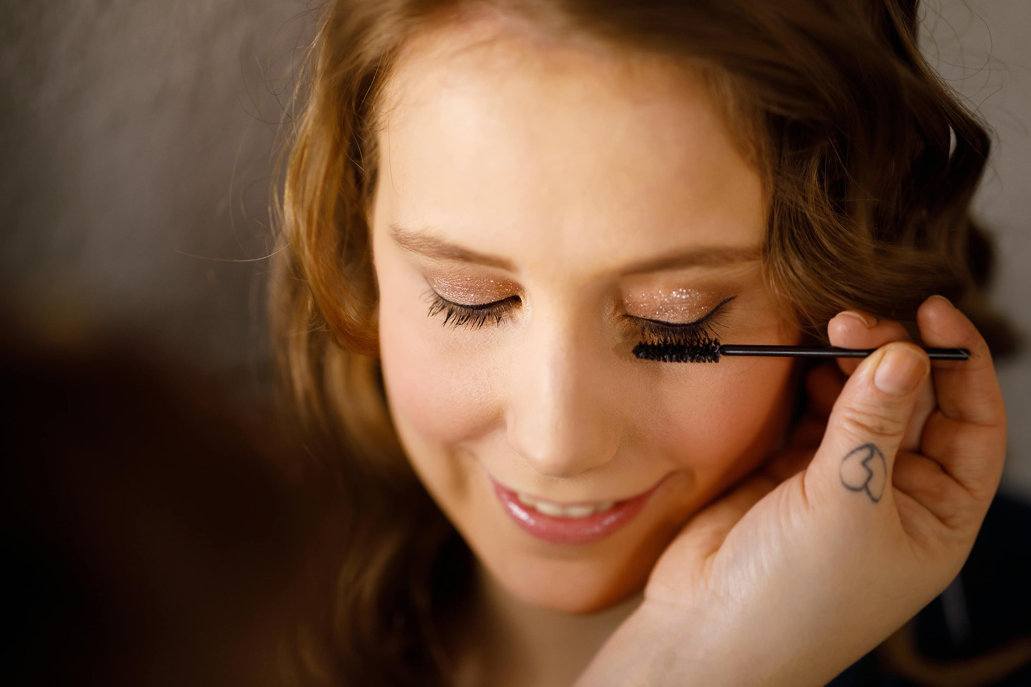 bride has her makeup done while getting ready for wedding