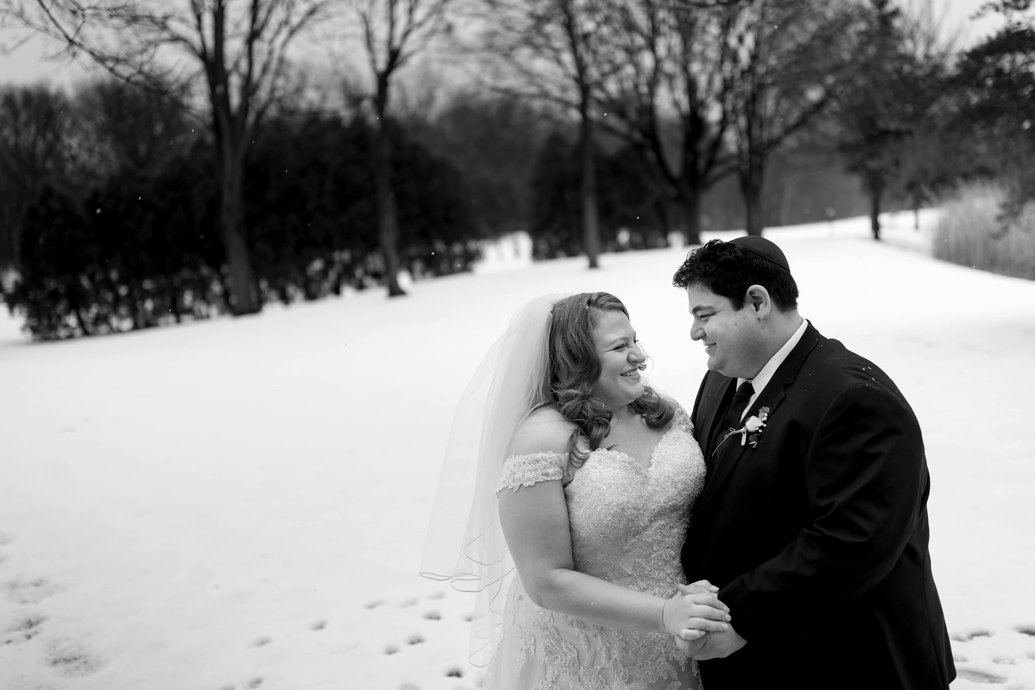 bride and groom pose for portrait with snow and trees in the background
