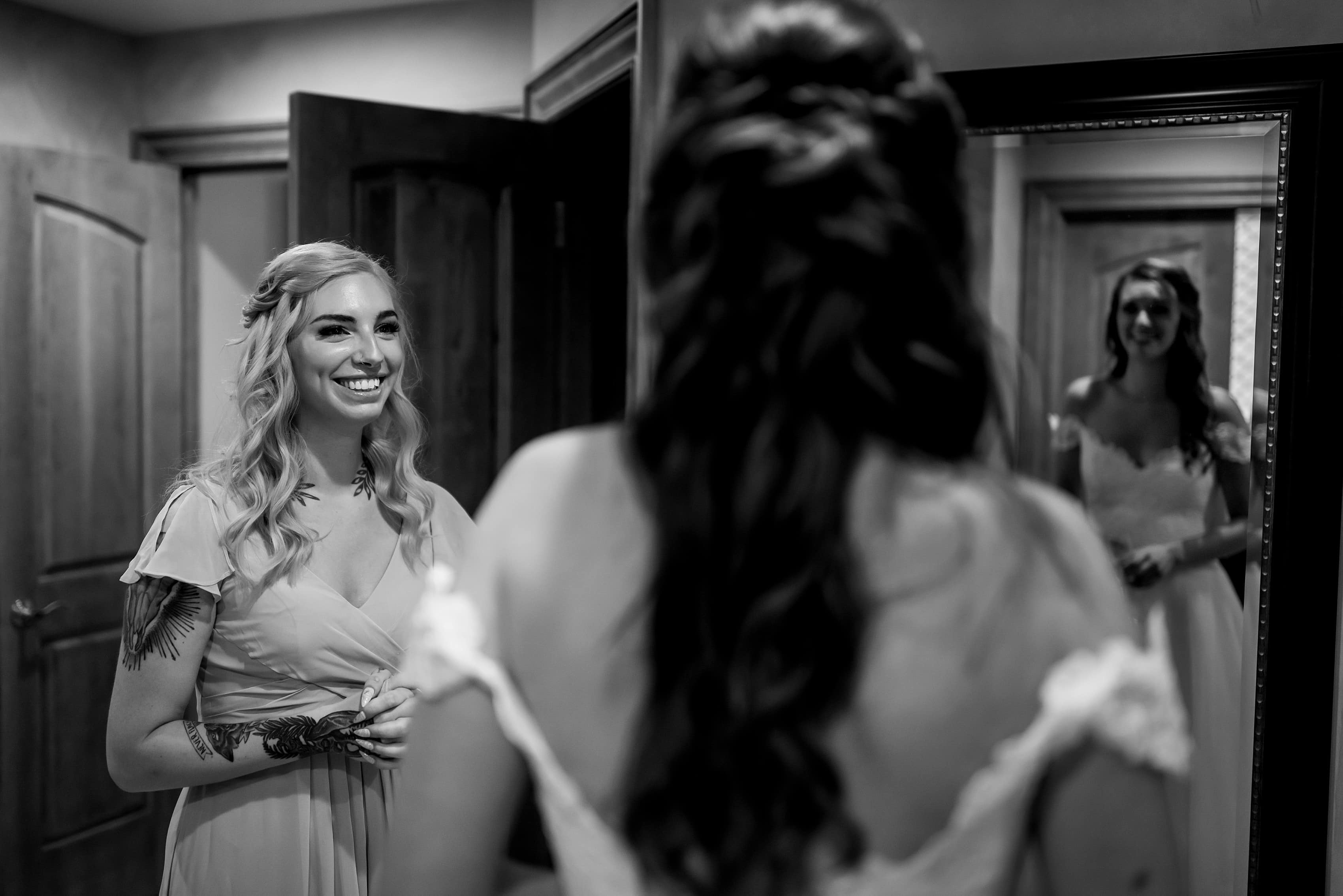 mother of bride and sister help bride into dress while getting ready