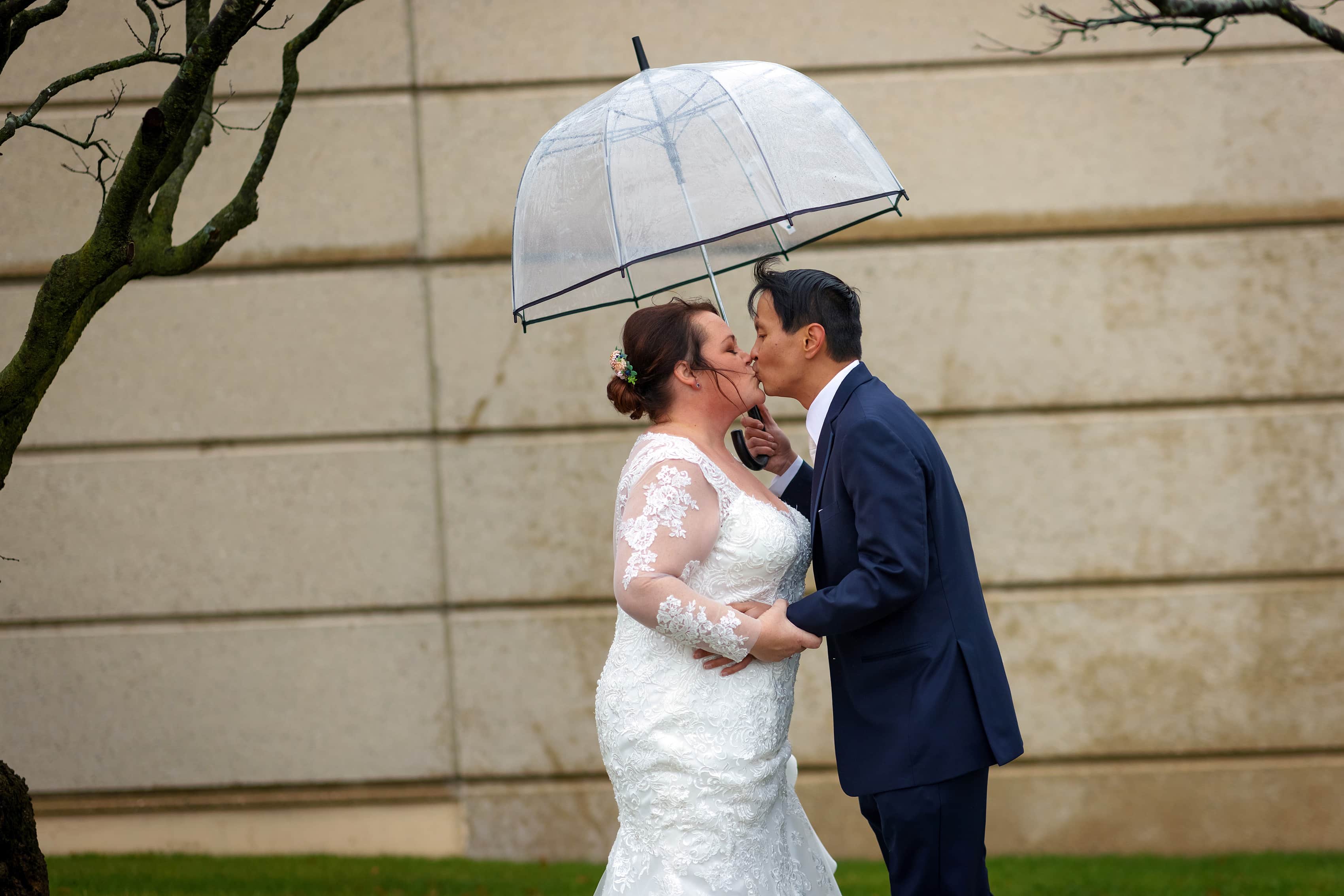 bride and groom kiss under umbrella