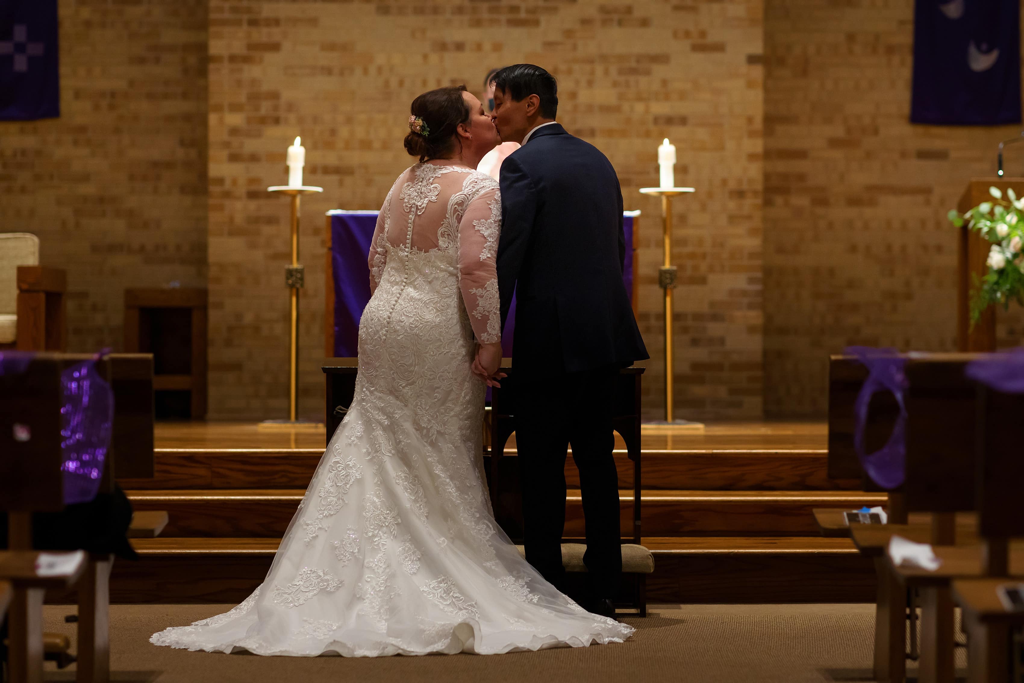 bride and groom share first kiss during wedding ceremony at St. Scholastica parish