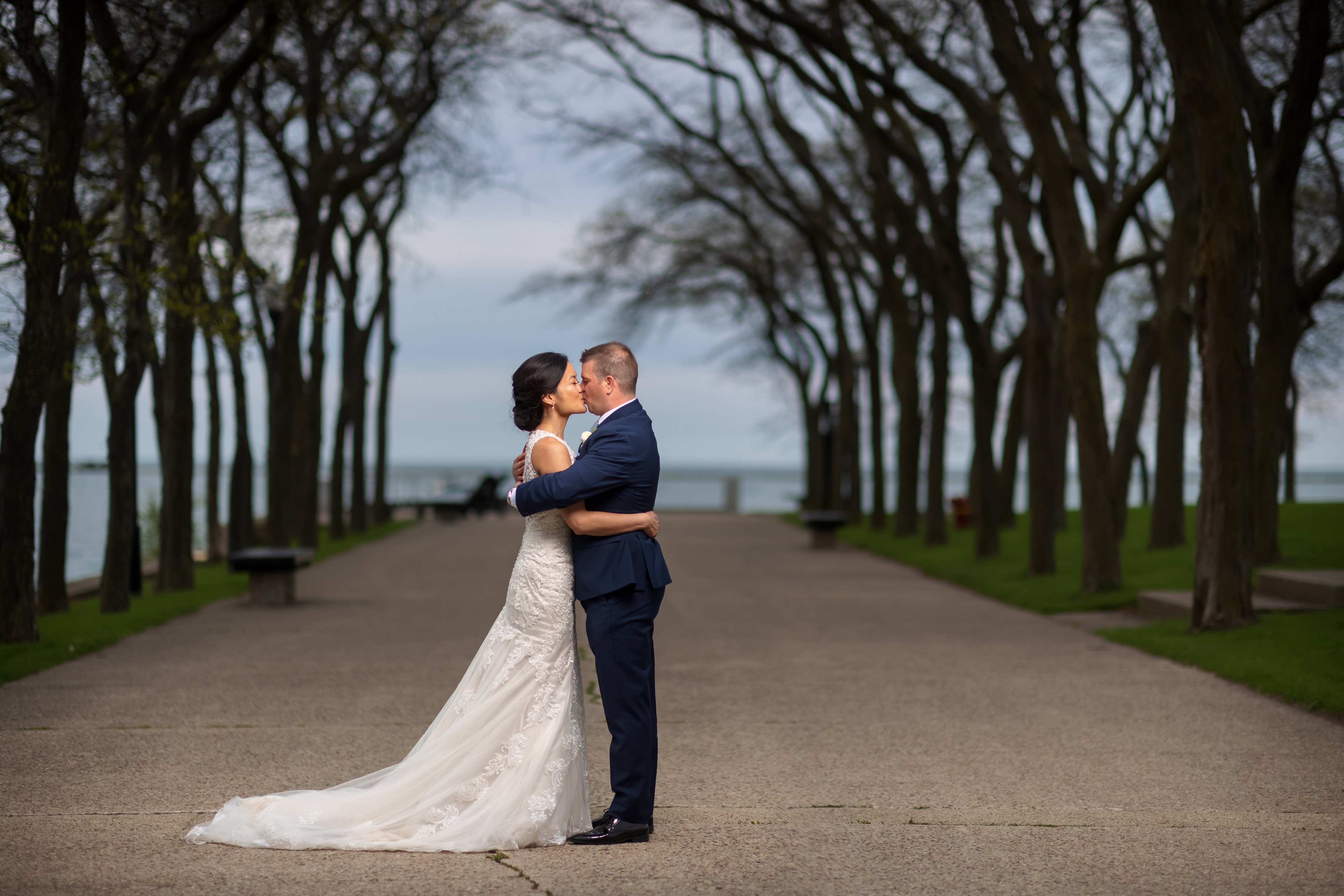 Bride and groom pose for wedding portrait at Milton Lee Olive Park in Chicago with skyline and lake in the background