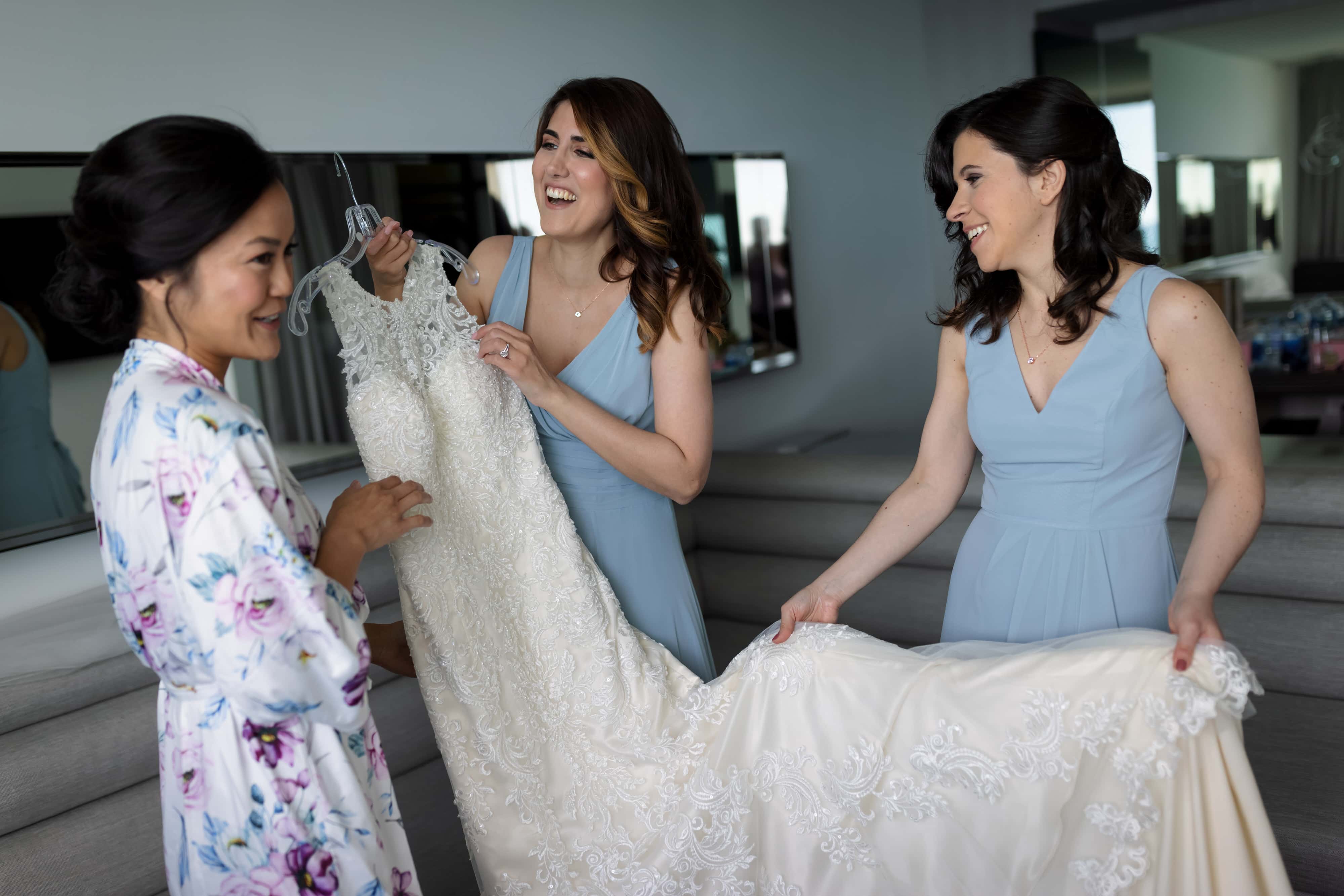 Bride and bridesmaids get ready to put on bridal gown