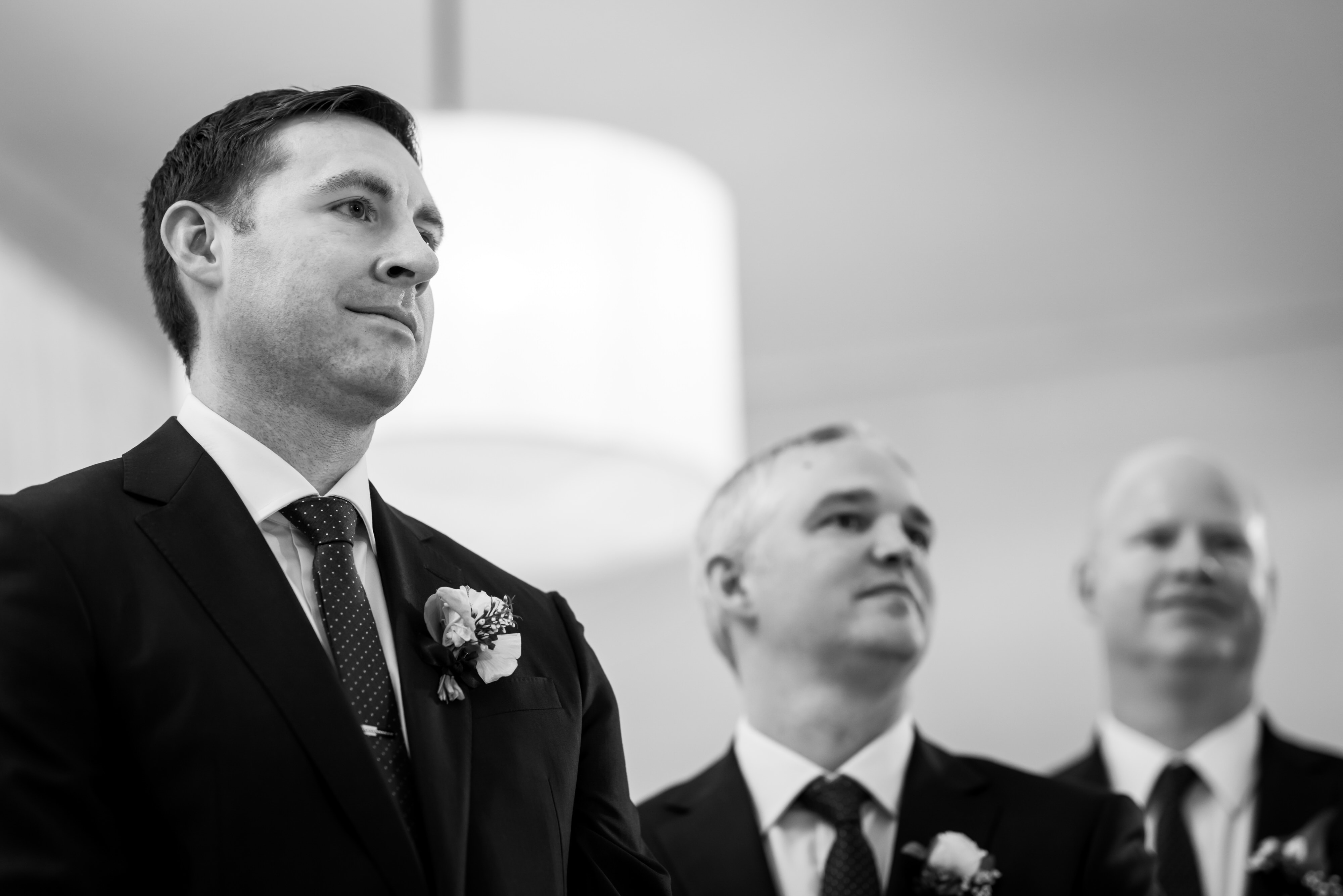 closeup of faces of groom and groomsman at front of aisle