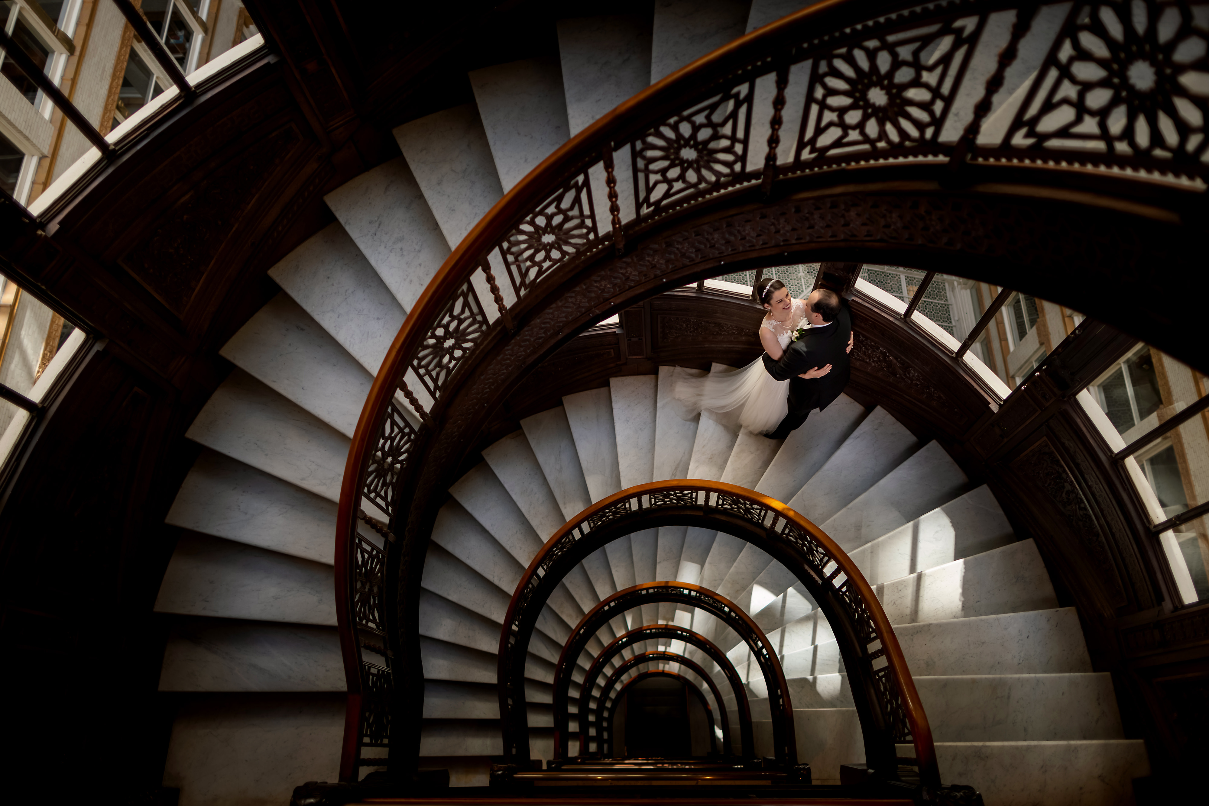 Bride and groom pose for portrait on the historic spiral staircase at the Rookery Building in downtown Chicago