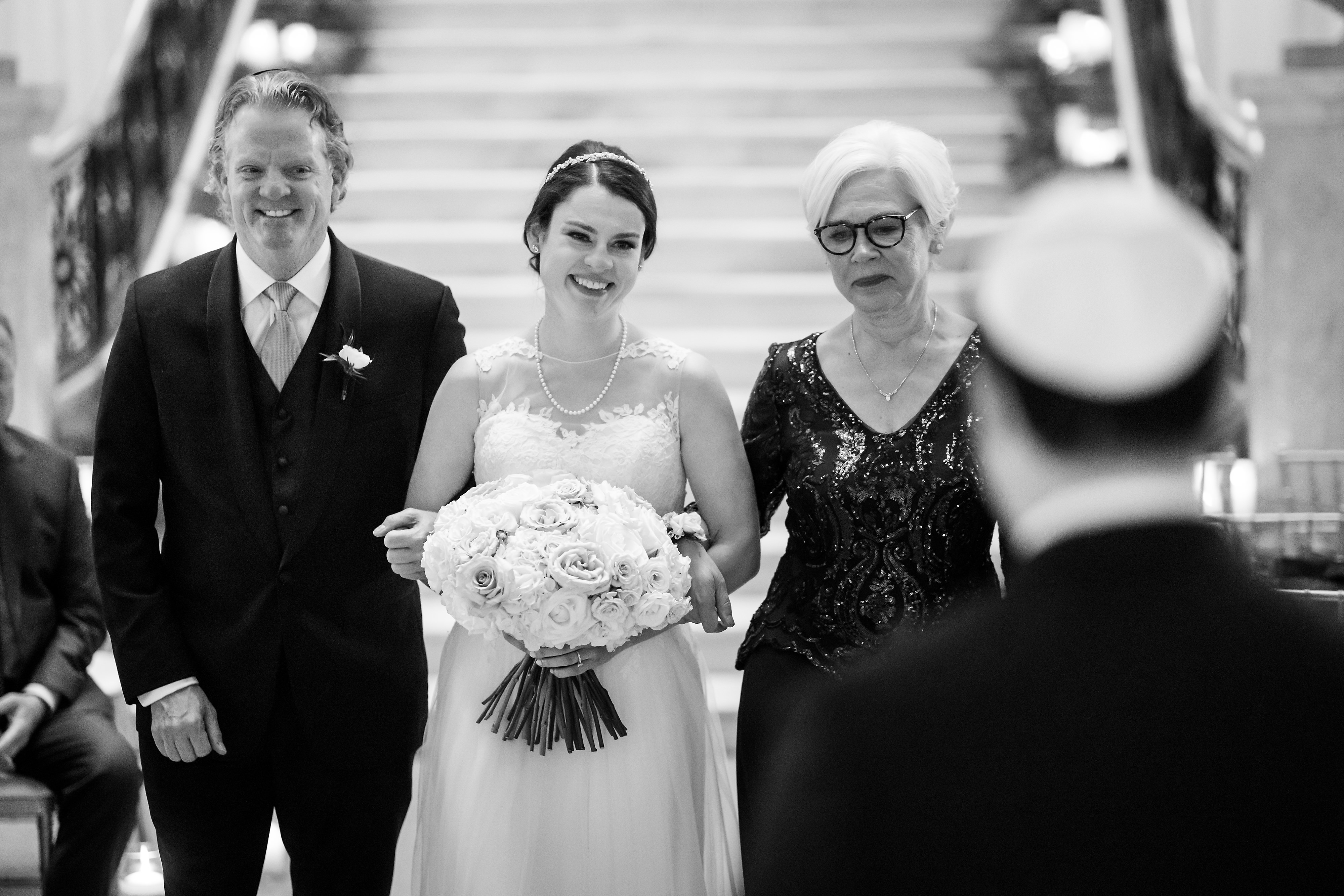 Bride walks in with parents during wedding ceremony at the Rookery Building in Chicago