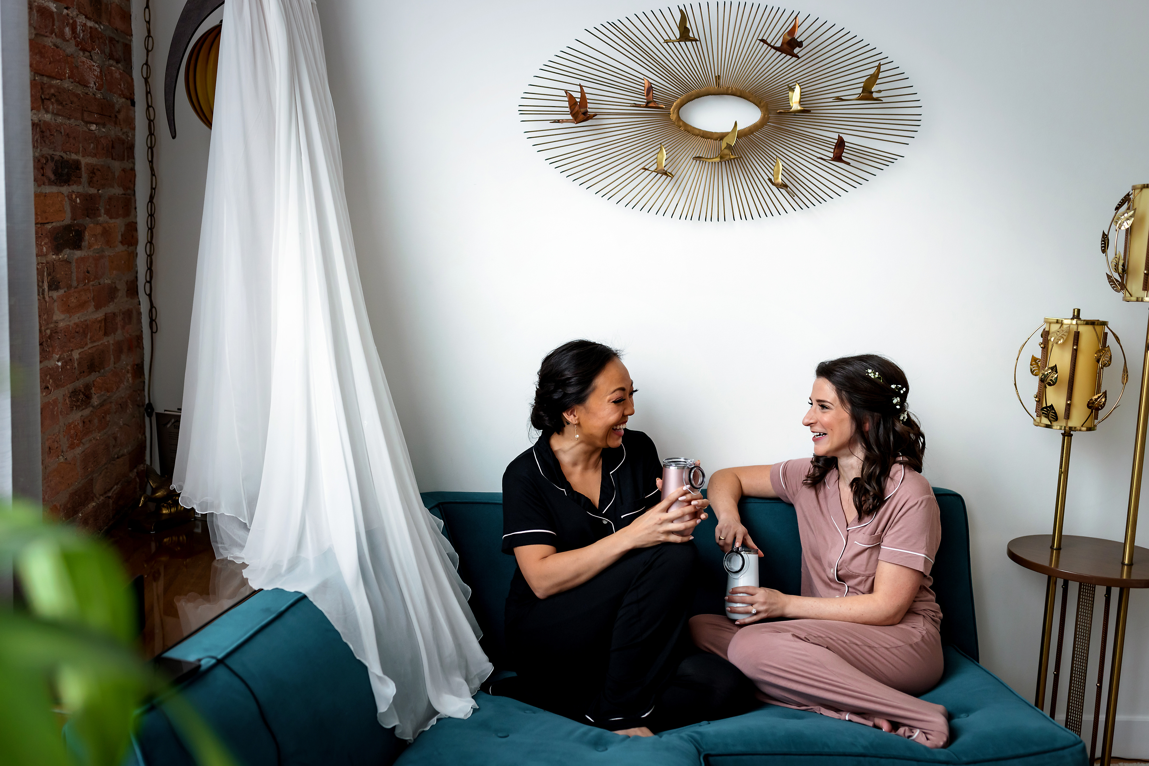 Bride and bridesmaid laugh while getting ready for a wedding at Publishing House Bed & Breakfast in Chicago's West Loop neighborhood.