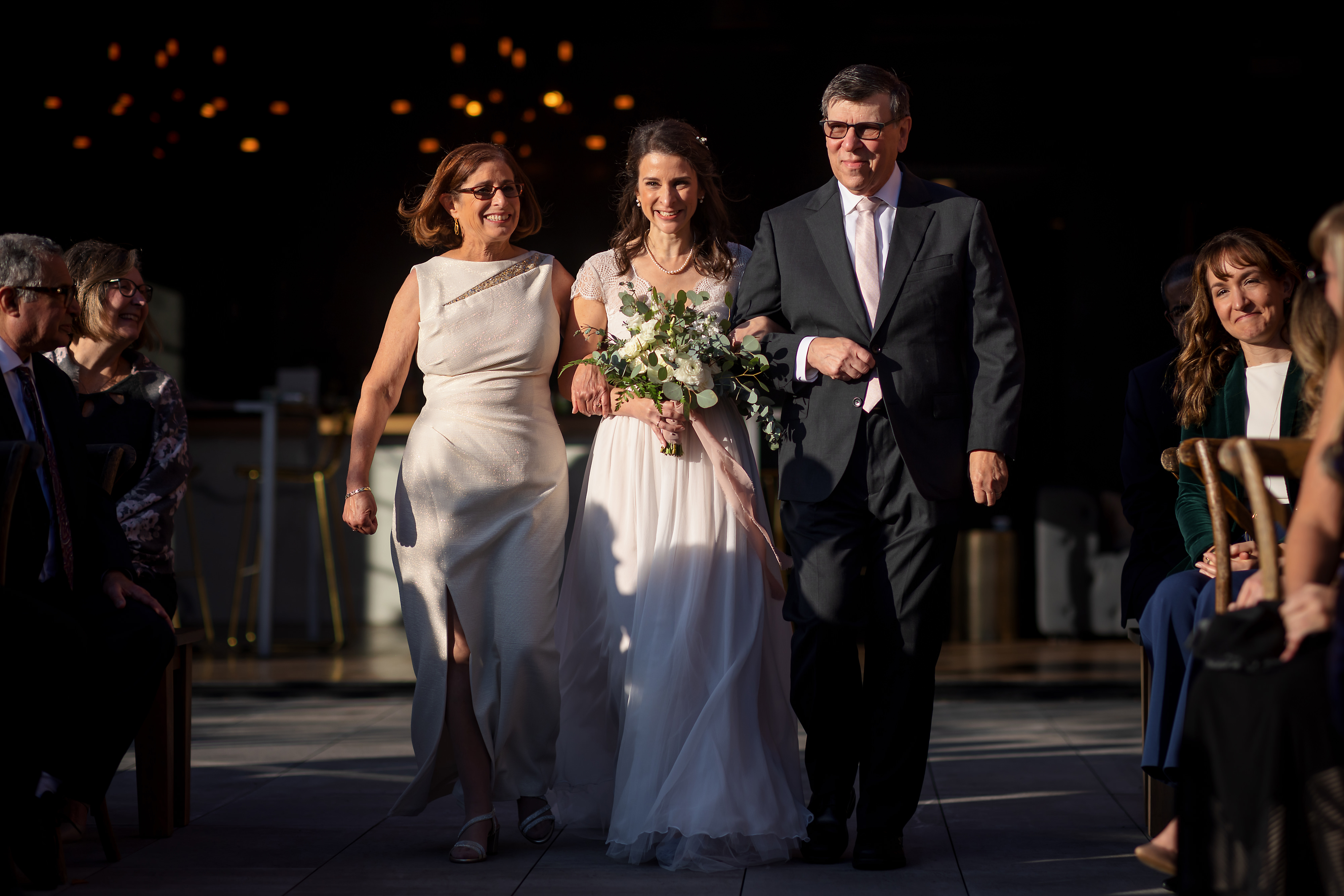Bride and parents walk down the aisle during wedding ceremony at Loft Lucia in Chicago's West Loop neighborhood.