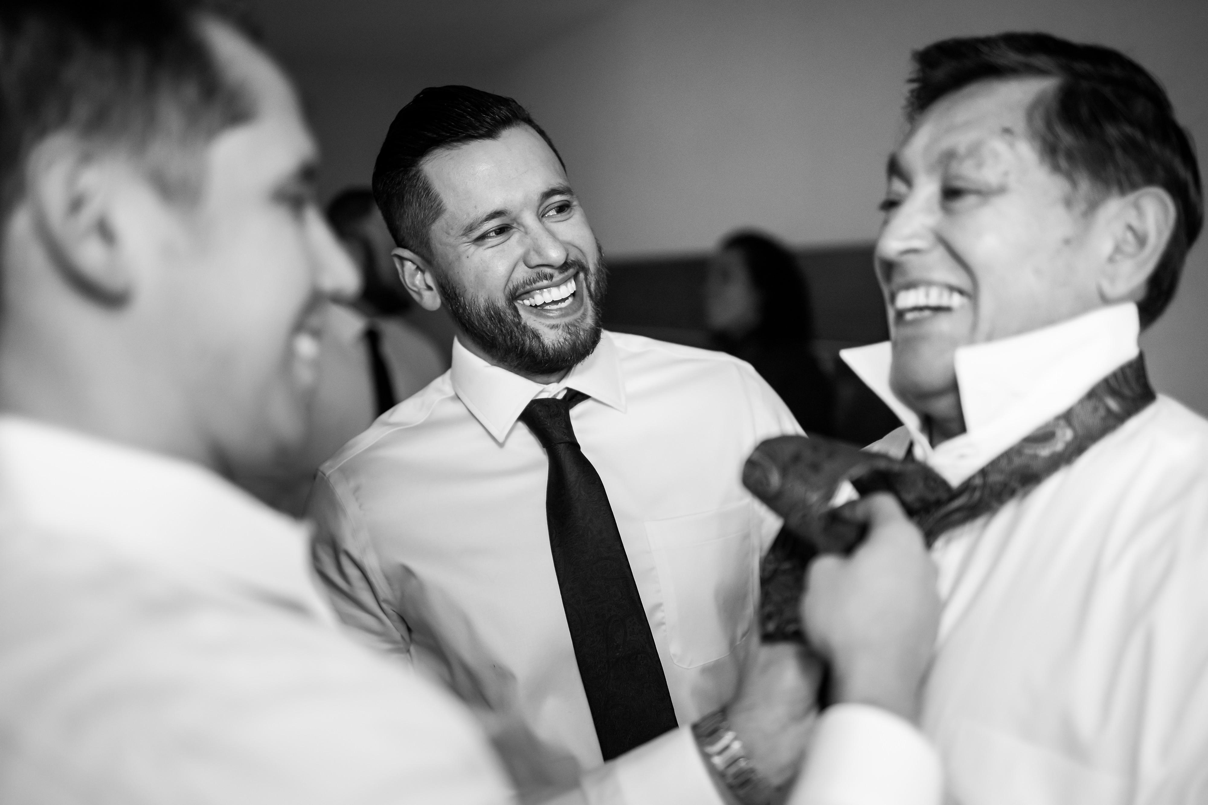 Groom and groomsmen put on ties while getting ready for wedding