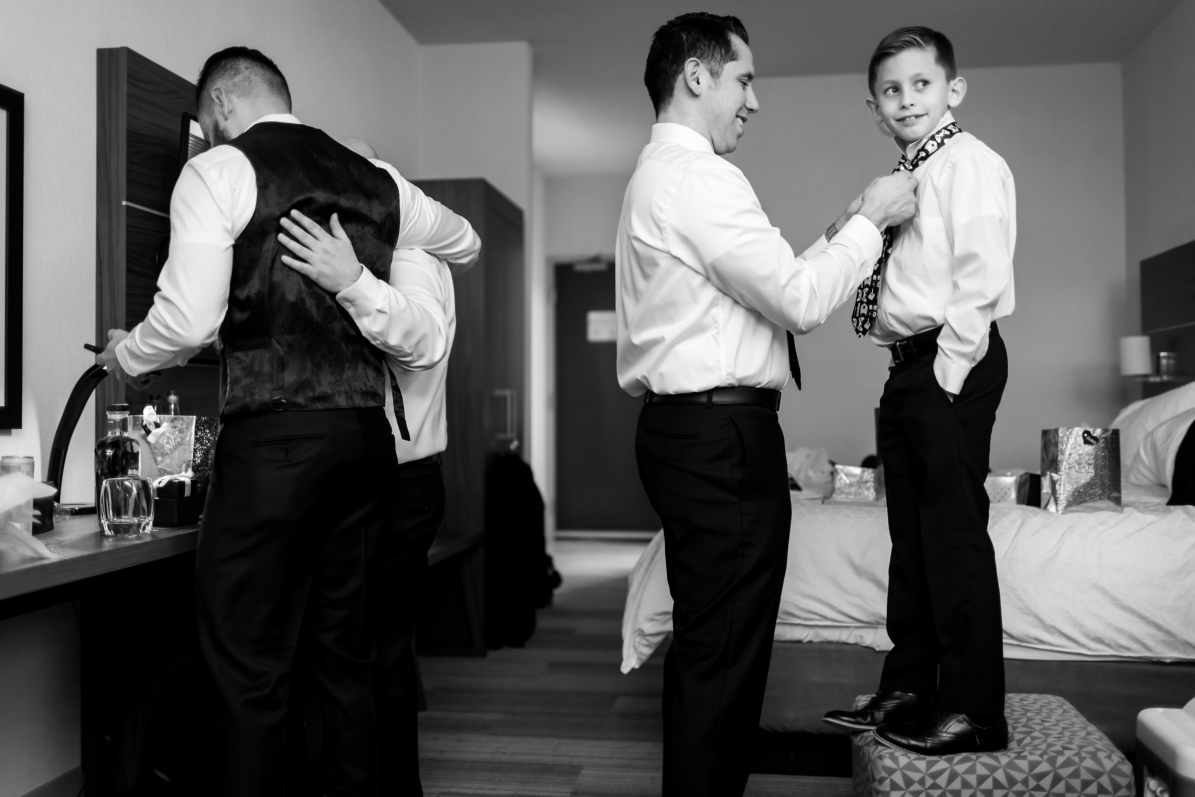 Groom and groomsmen put on ties while getting ready for wedding