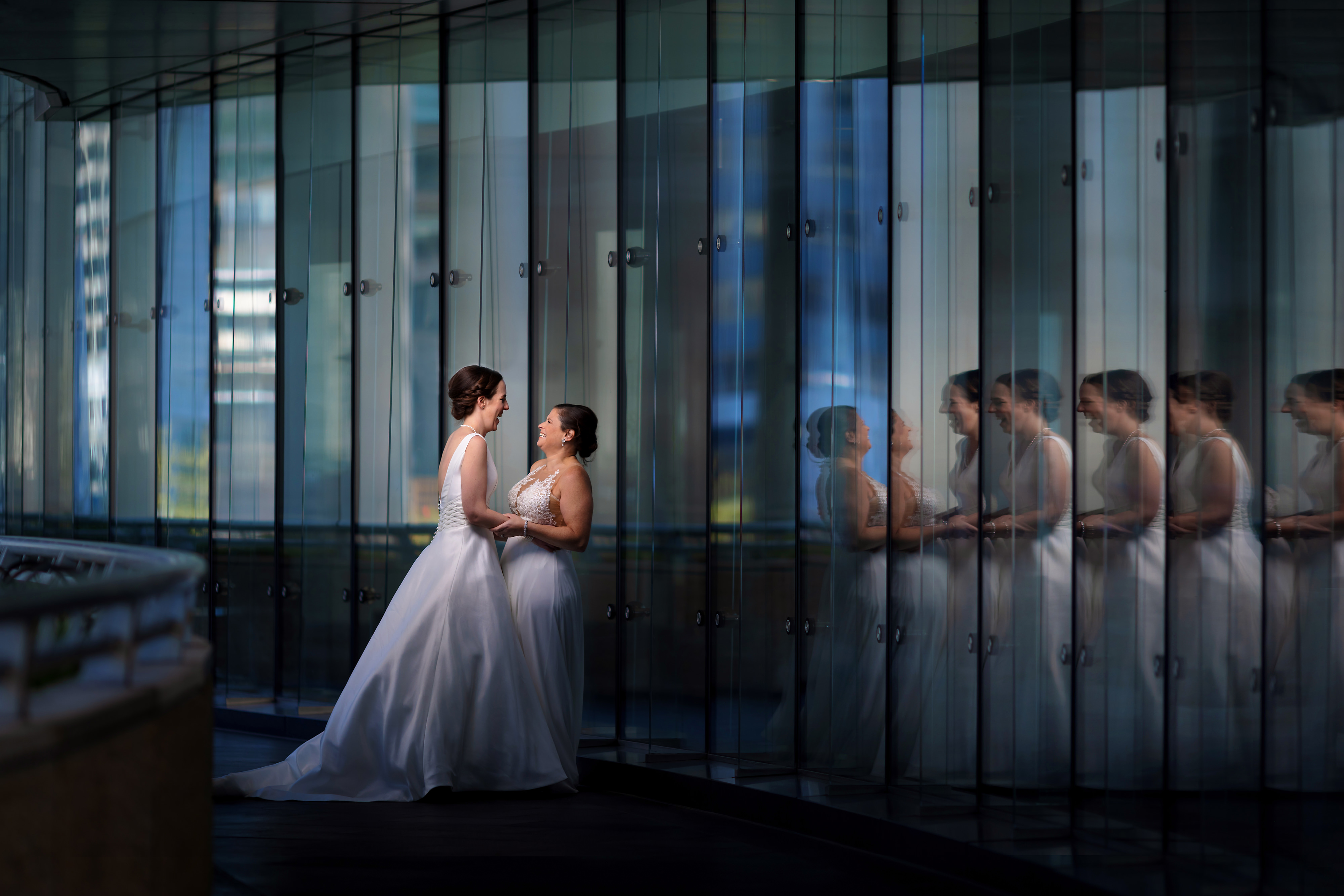 Two brides laugh during wedding portraits along the riverwalk in downtown Chicago