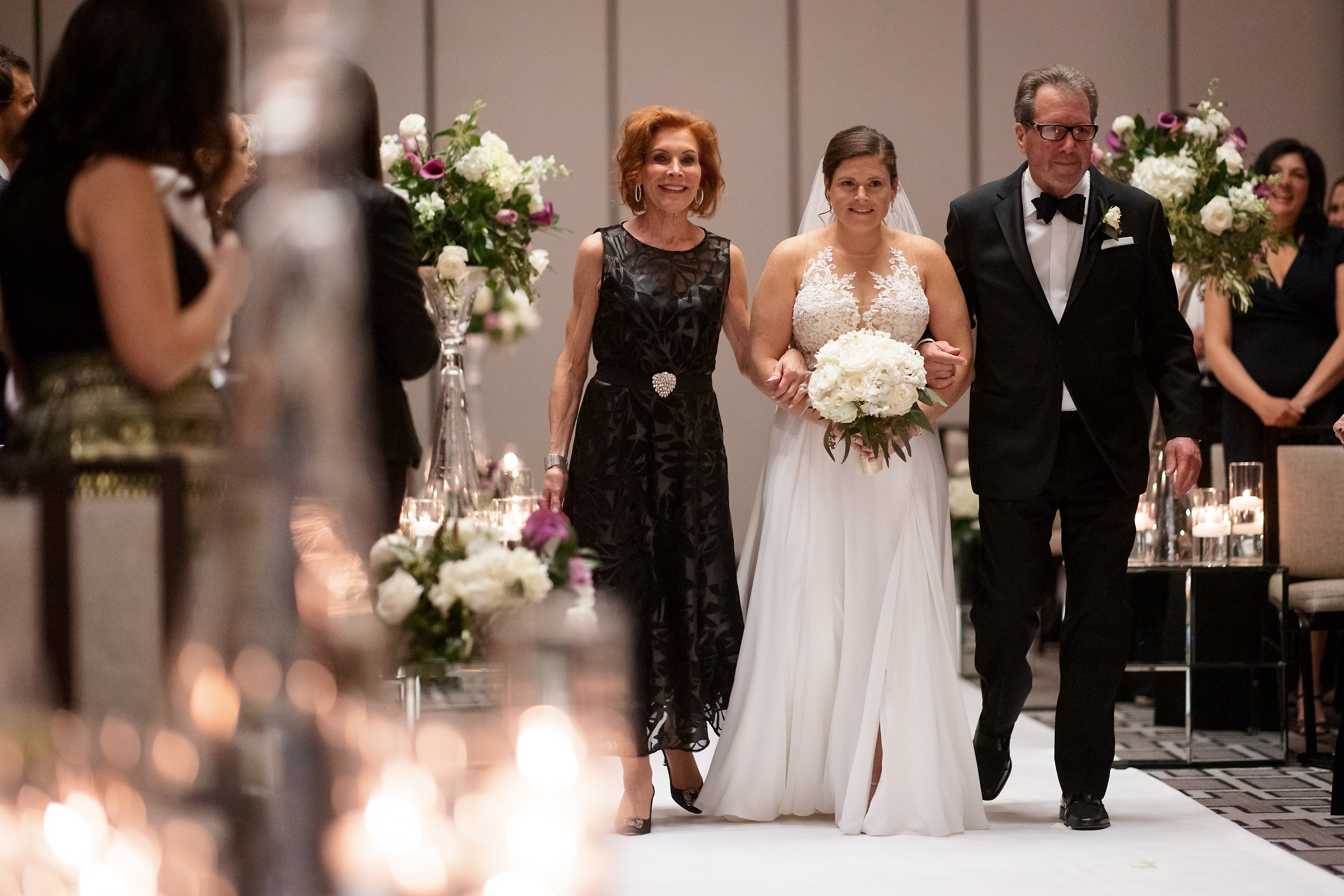 Bride walks down the aisle with her parents during wedding ceremony at The Langham Hotel in downtown Chicago