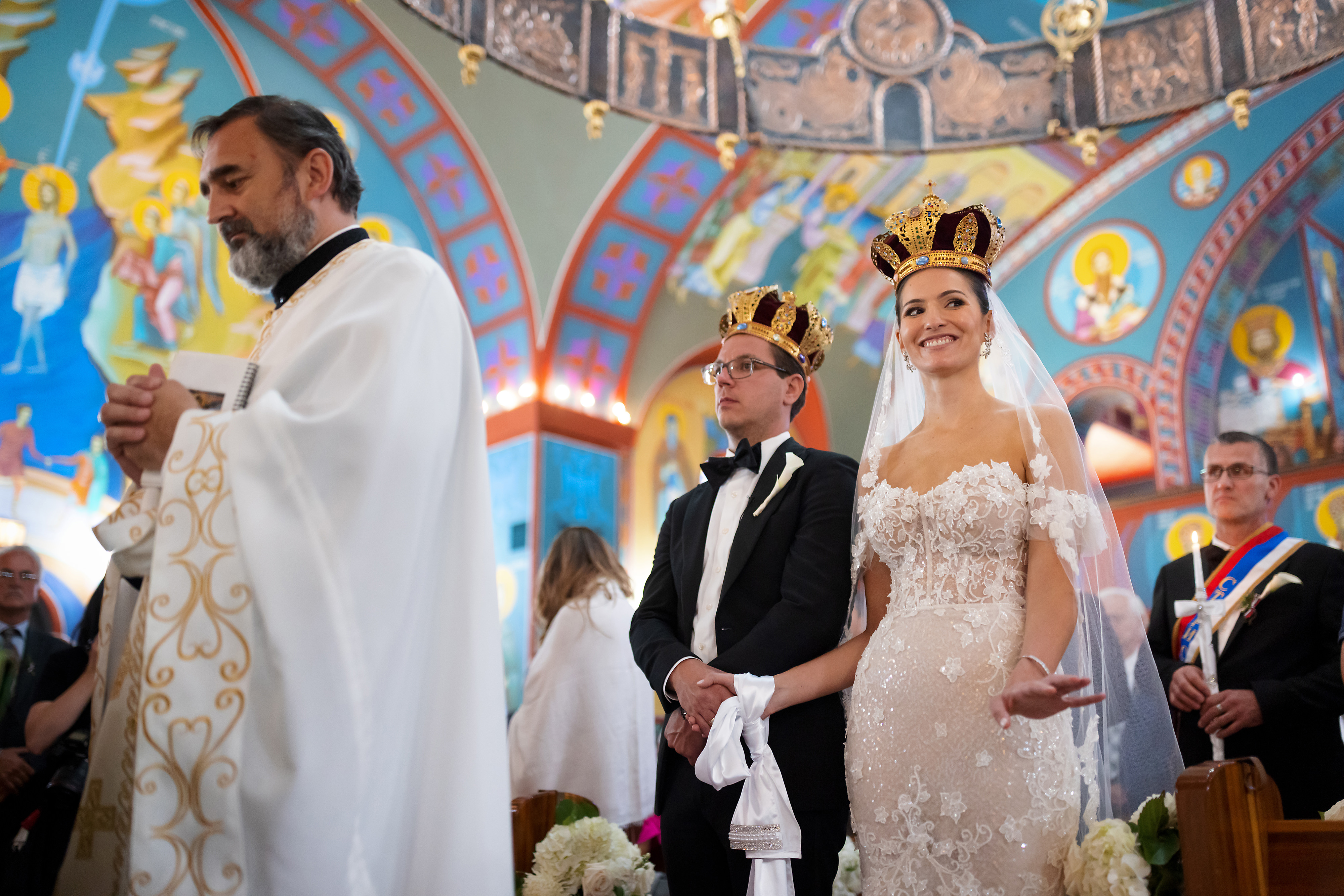Bride gestures to family during wedding ceremony at George Serbian Orthodox Church