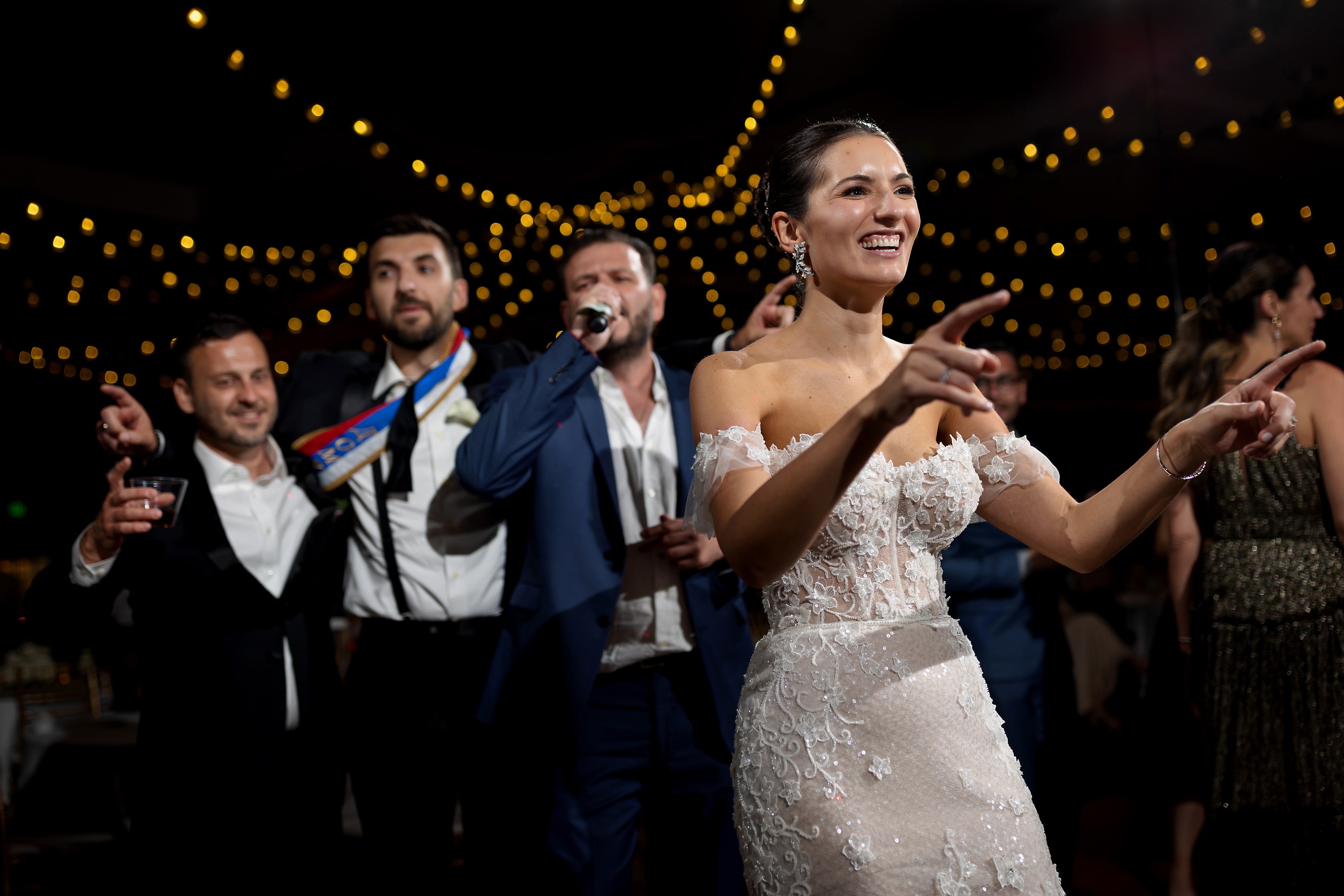 bride dances in front of wedding guests while they sing during wedding reception at Halls of St. George in Schererville, Indiana