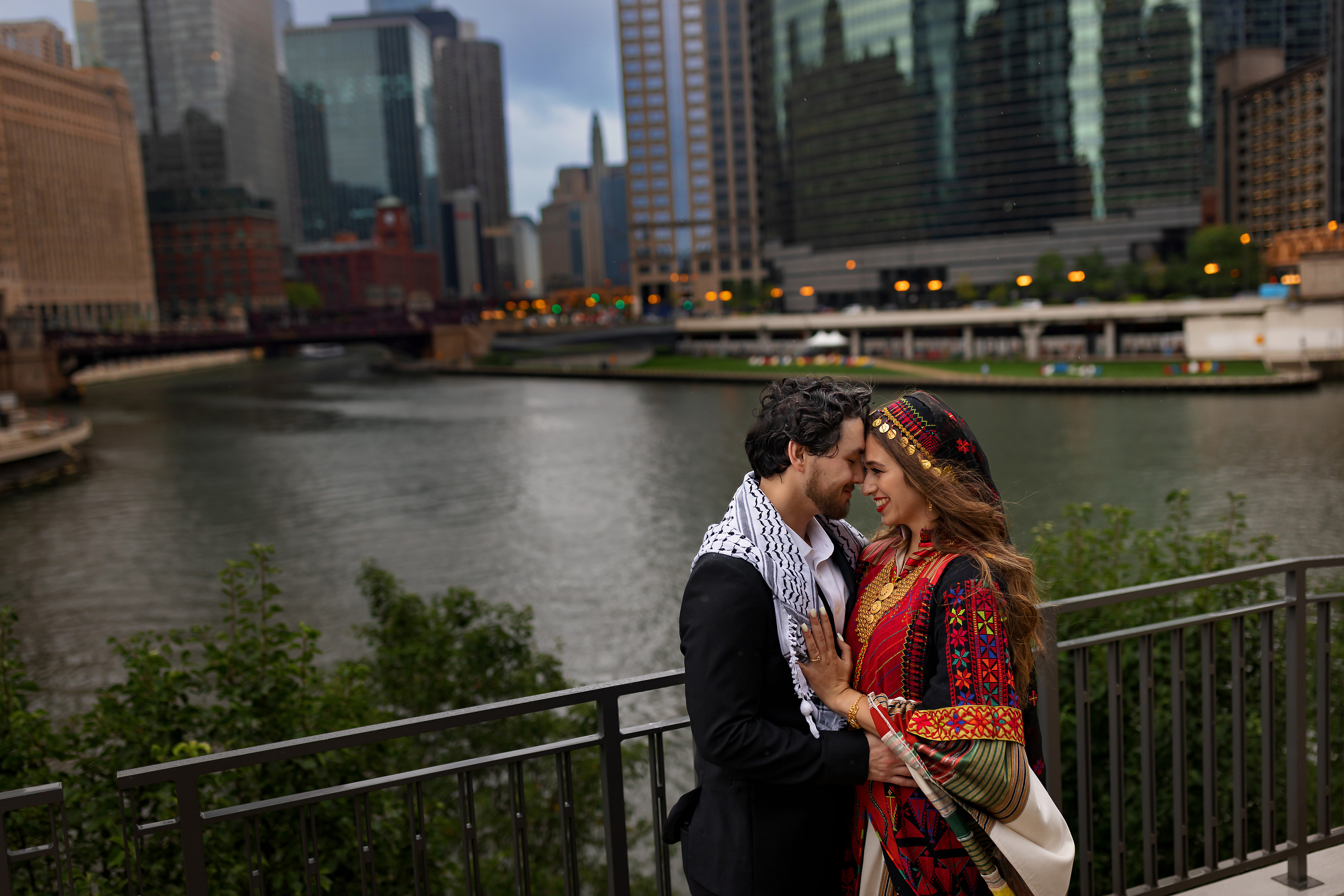 Bride and groom pose for photos near Gibson's Italia Plaza Riverwalk with the Chicago skyline and river in the background