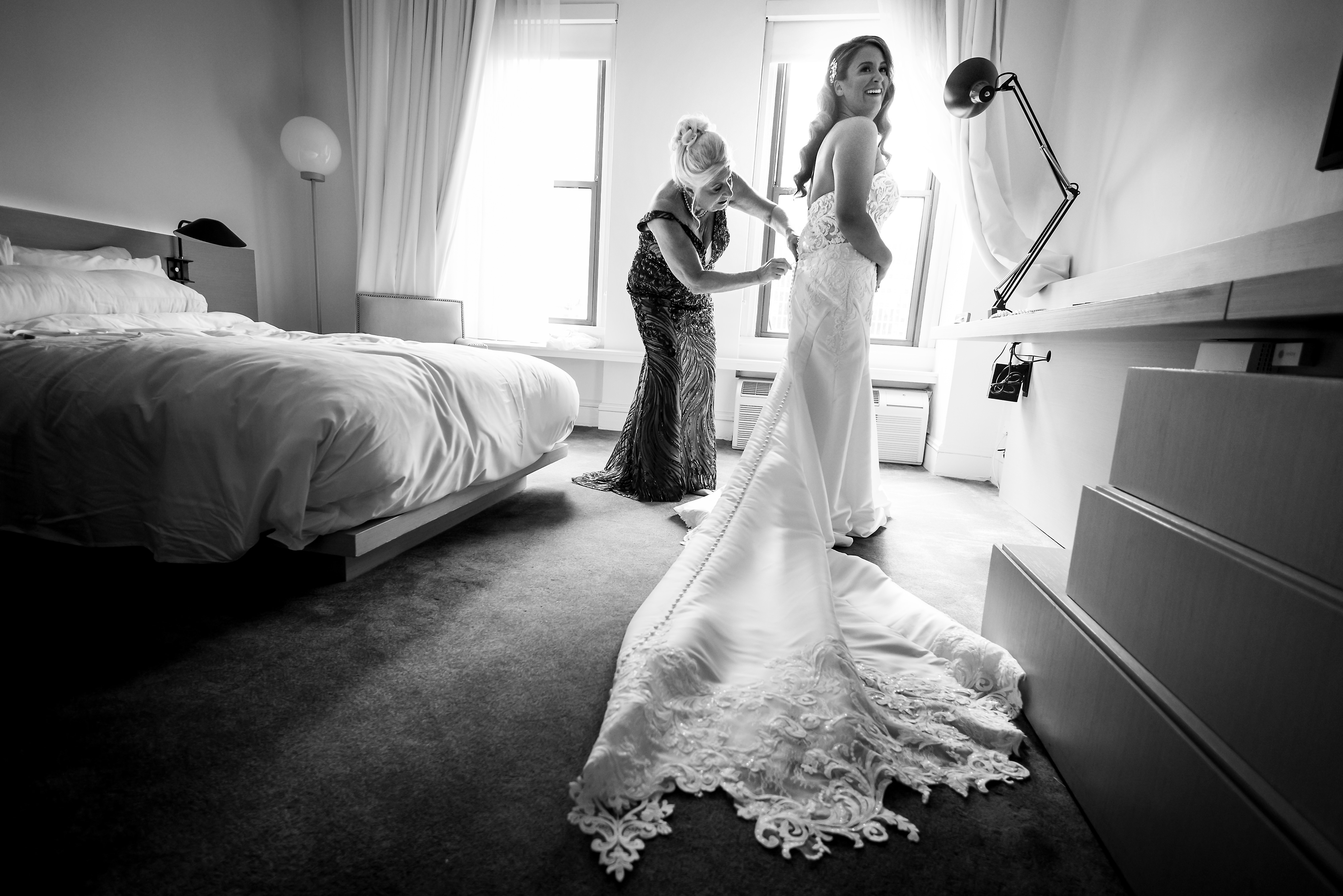 Bride and mother get into wedding dress while getting ready at Ambassador Hotel Chicago.