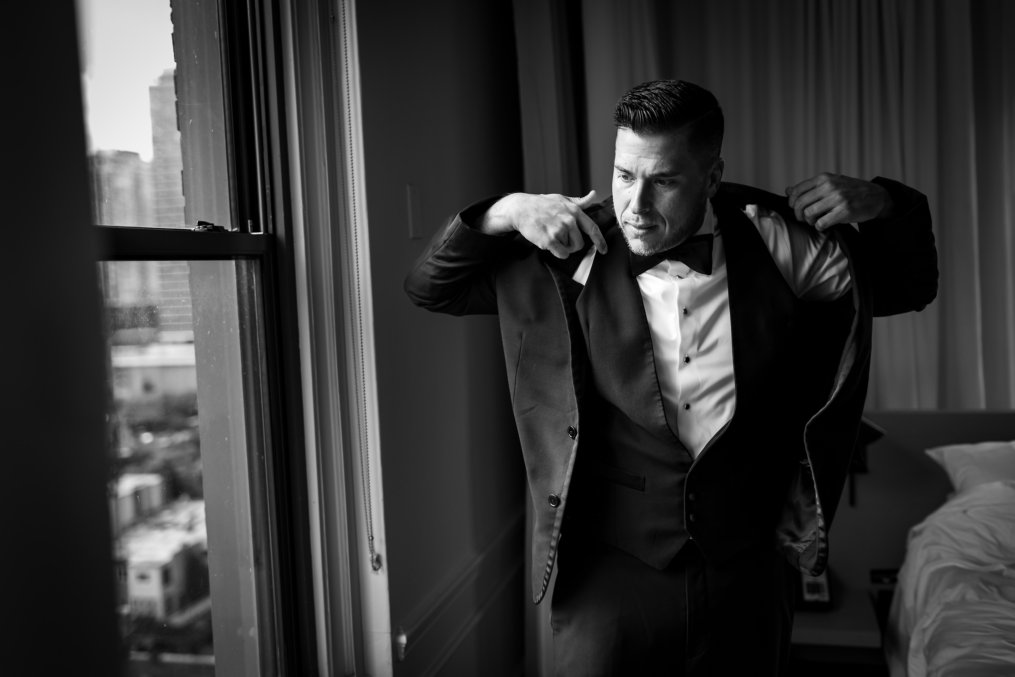 Groom puts on jacket in preparation for wedding at Ambassador Hotel Chicago.