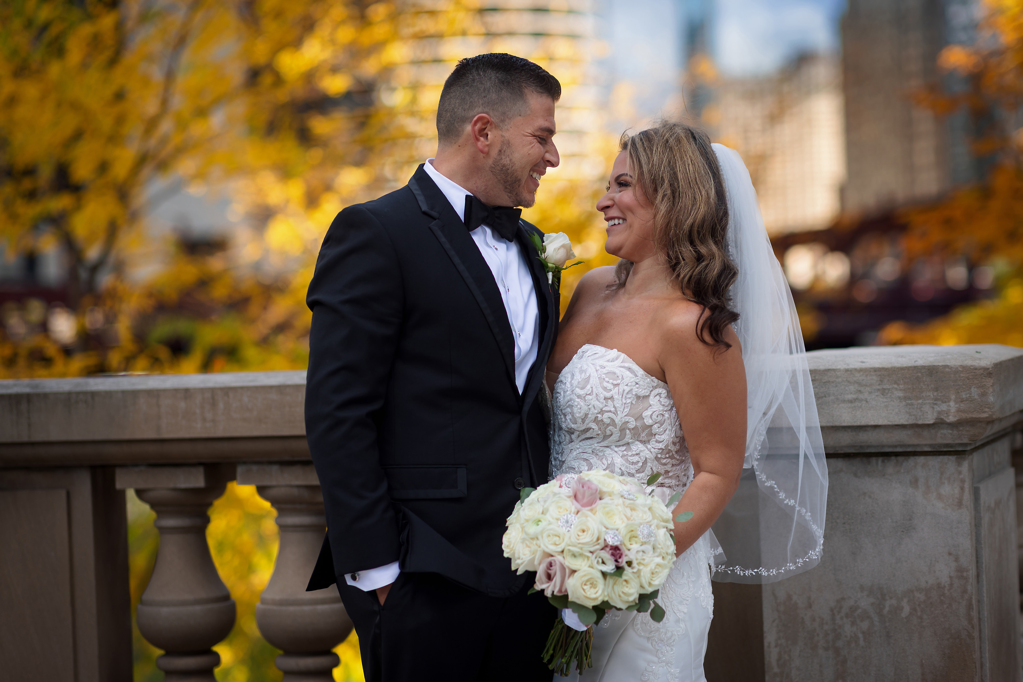 Bride and groom on LaSalle street in downtown Chicago during wedding portraits with fall color trees in background.